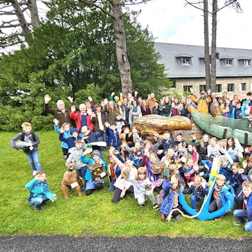 Schüler, Lehrer und Mitarbeiter der Nationalparkverwaltung stehen und sitzen um die Glasarche herum.