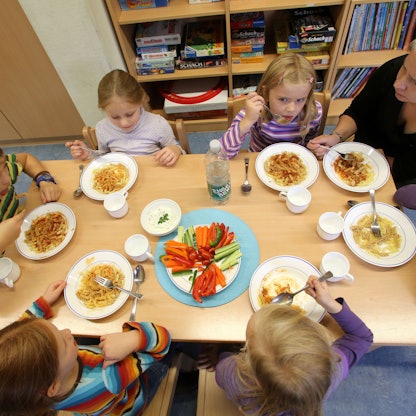 Kinder sitzen zum gemeinsamen Essen an einem Tisch,