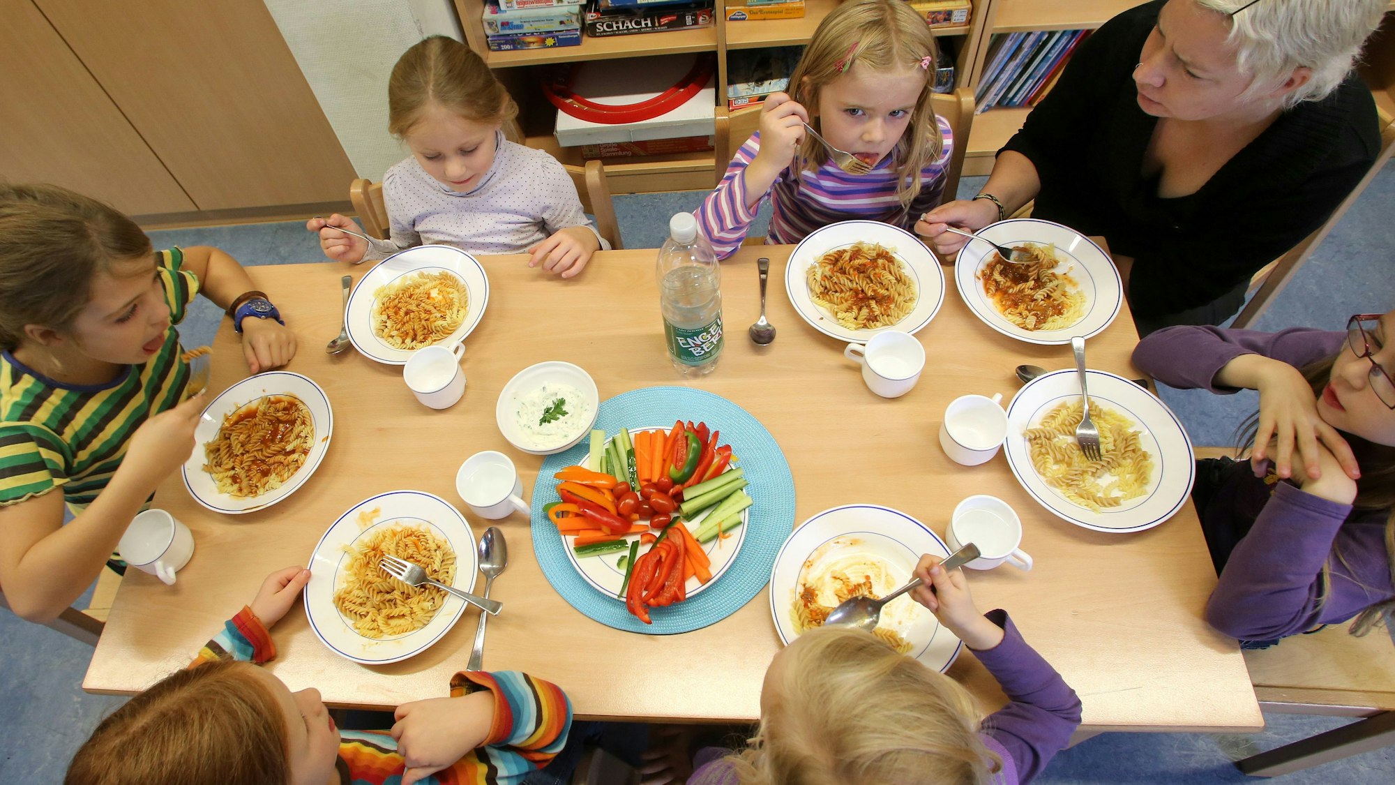 Kinder sitzen zum gemeinsamen Essen an einem Tisch,