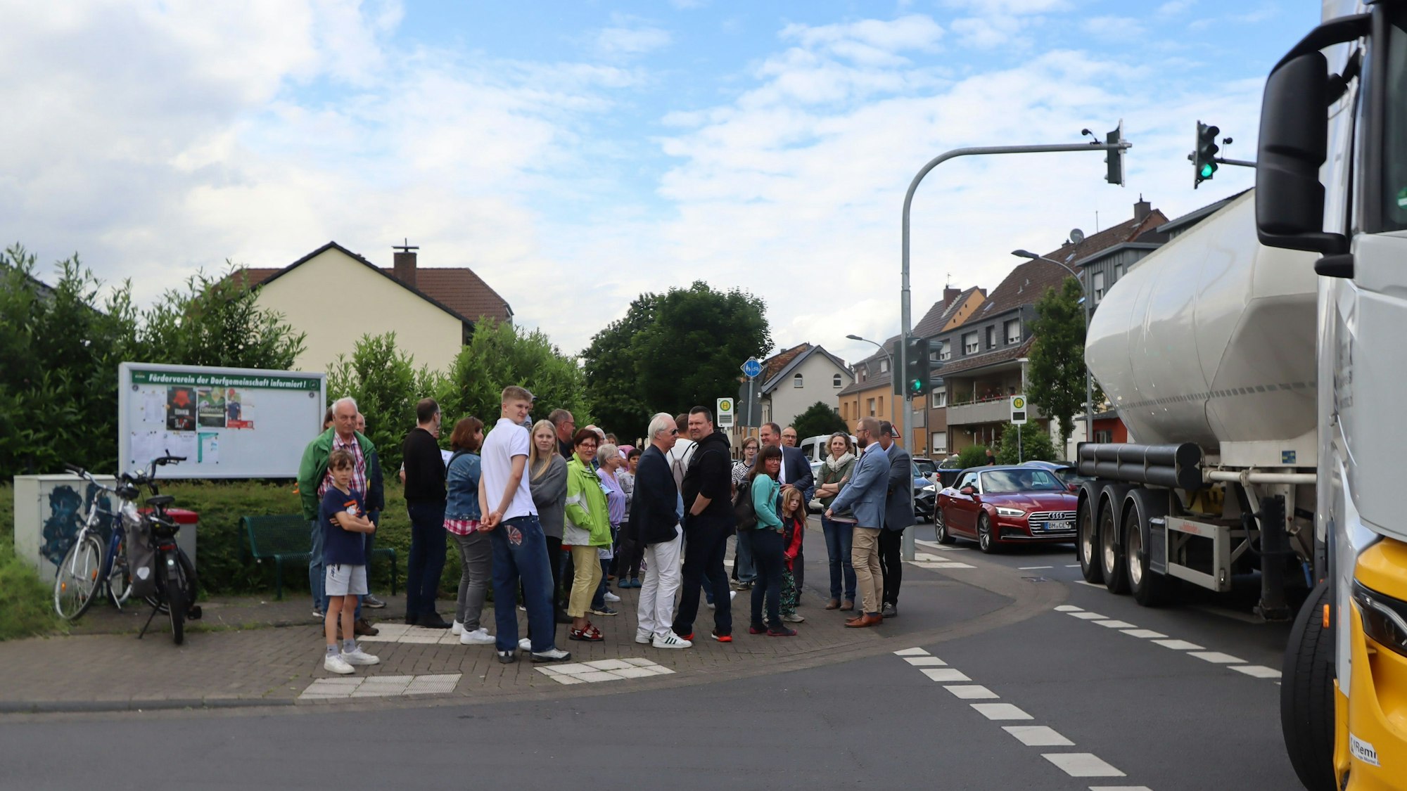 Eine Gruppe von Menschen steht an einer Kreuzung, ein großer Lastwagen biegt gerade ab.