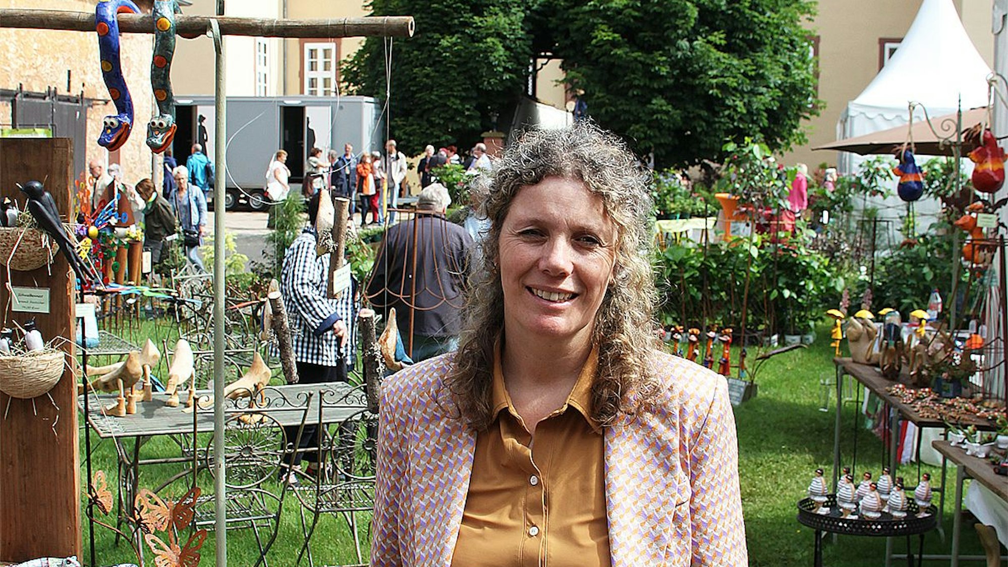 Marjon Nijkamp steht auf dem Außengelände des Schloss Eicks bei Mechernich. Um sie herum sind einige Stände der Veranstaltung „Gartenträume“ zu sehen.
