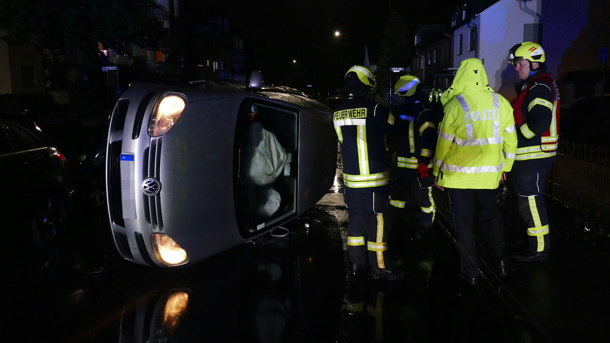 Feuerwehrleute und Polizisten stehen neben dem umgekippten Fahrzeug.