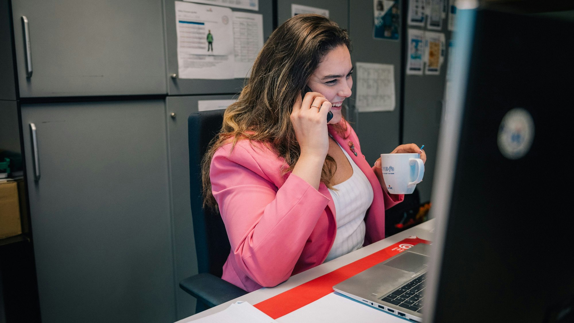 Eine Frau sitzt auf der Arbeit vor einem Bildschirm.