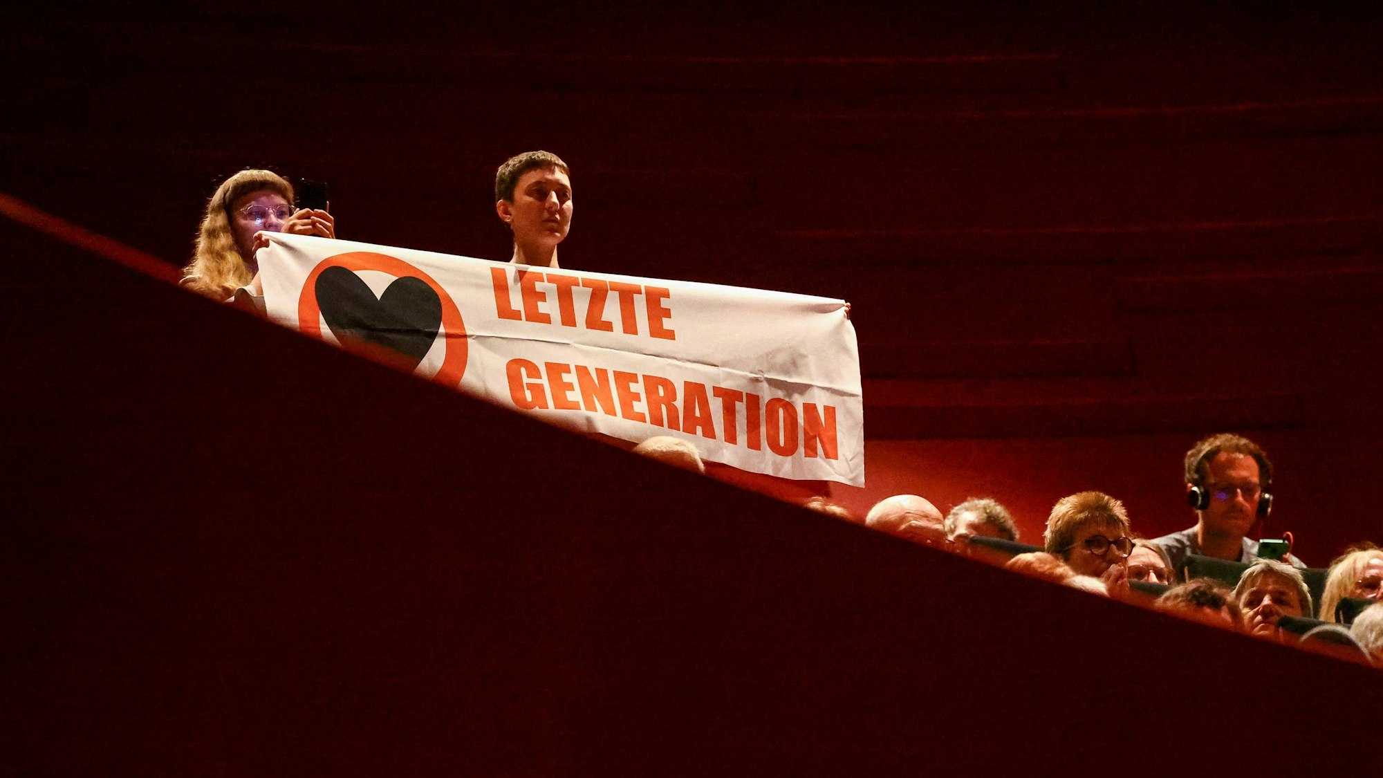 An activist from the "Letzte Generation" (Last Generation) holds a banner as German Chancellor Olaf Scholz attends Katholikentag, a gathering of German Catholics, in Erfurt, Germany, Friday, May 31, 2024. (Kai Pfaffenbach/Pool Photo via AP)