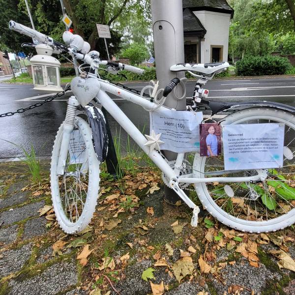 Ein weiß lackiertes Fahrrad ist an einem Laternenmast befestigt.
