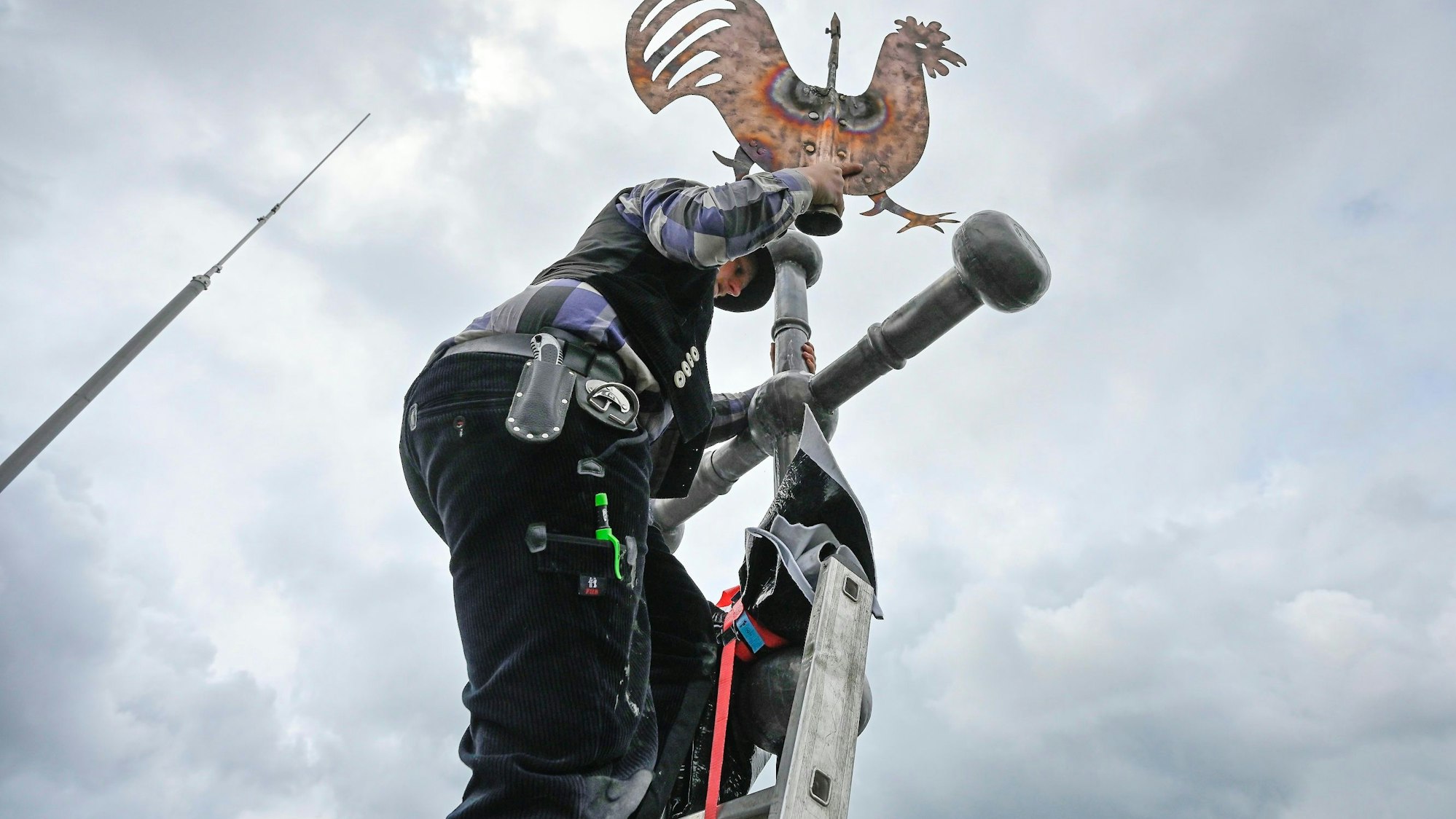 Mann mit Wetterhahn auf einem Kirchturm
