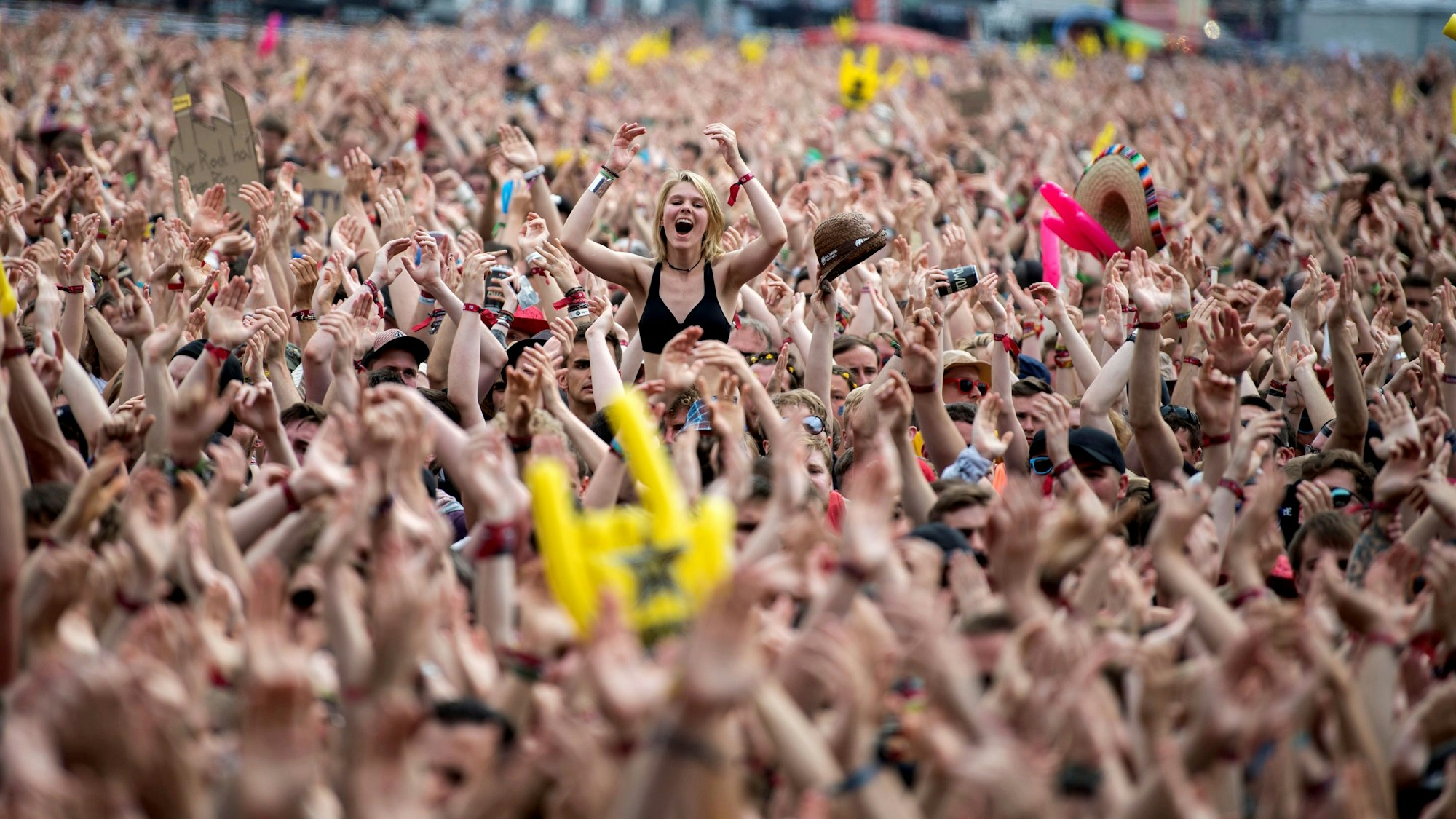 Das Bild zeigt die Menschenmenge vor der Hauptbühne. Eine Frau ragt aus der Masse an nach oben gehaltenen Armen hervor.