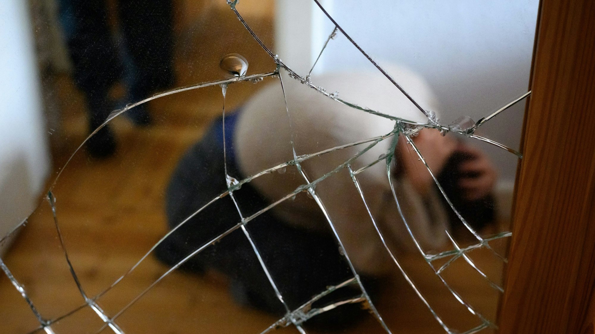 Ein Mann steht neben einer Frau, die am Boden mit ihren Händen ihren Kopf schützt (Illustration).