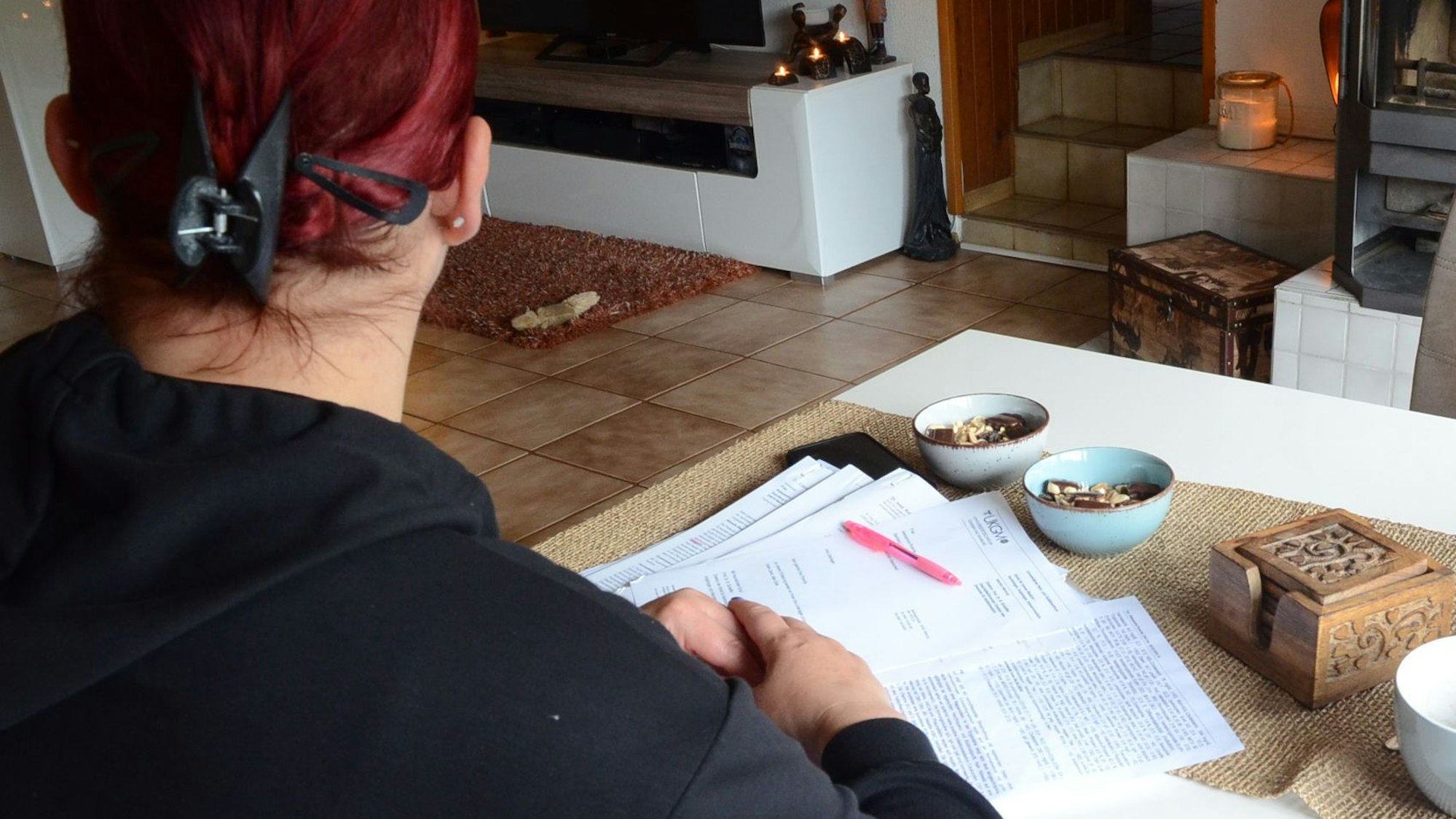 Eine Frau sitzt an einem Tisch, sie hat Briefe und Gutachten vor sich auf dem Tisch liegen.