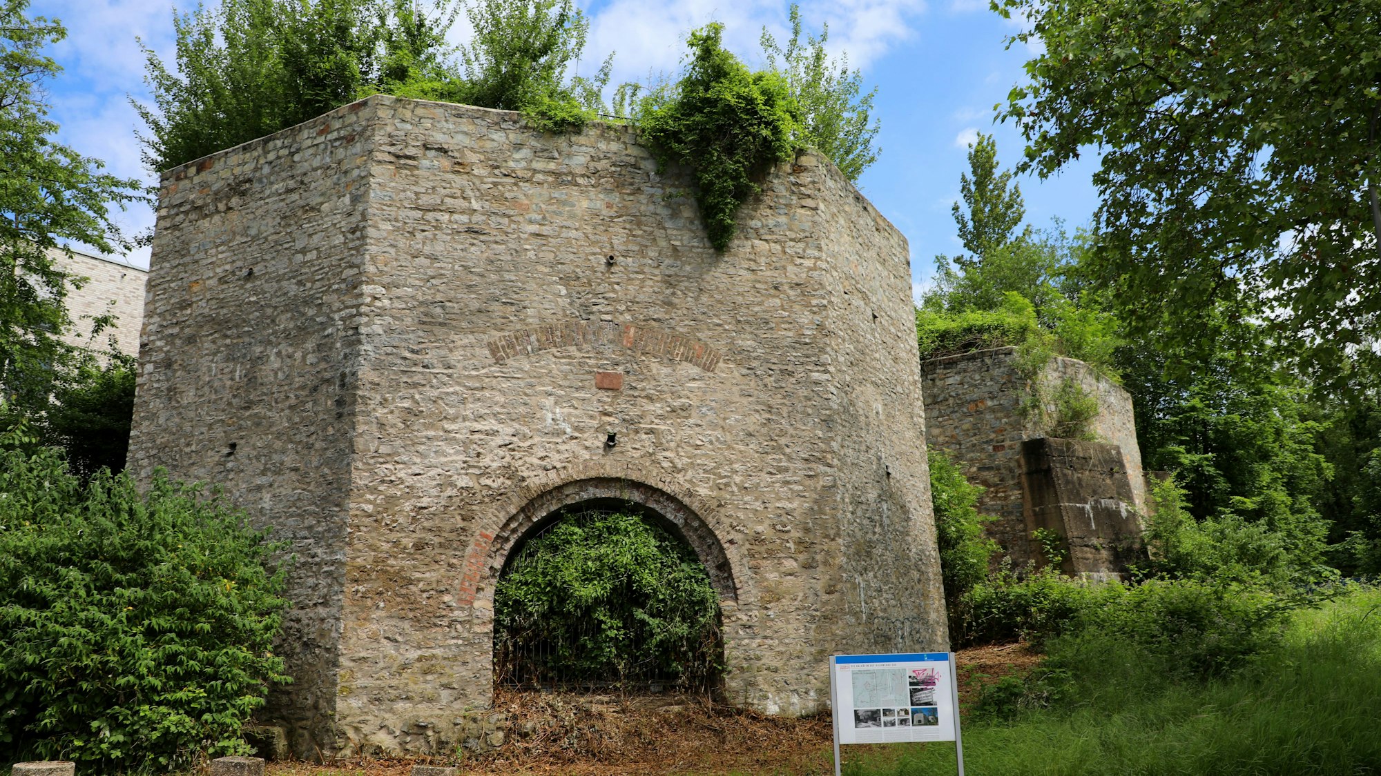 Vor den historische Kalköfen der Grube Cox unweit des Bergisch Gladbacher S-Bahnhofs steht eine Infotafel.
