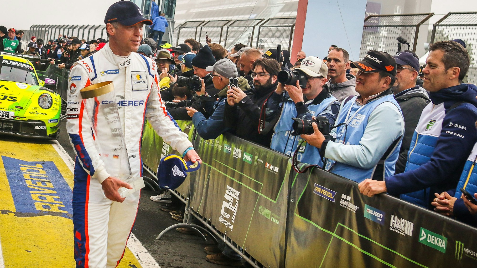Rennfahrer Frank Stippler steht mit einem Pokal vor den Fotografen.