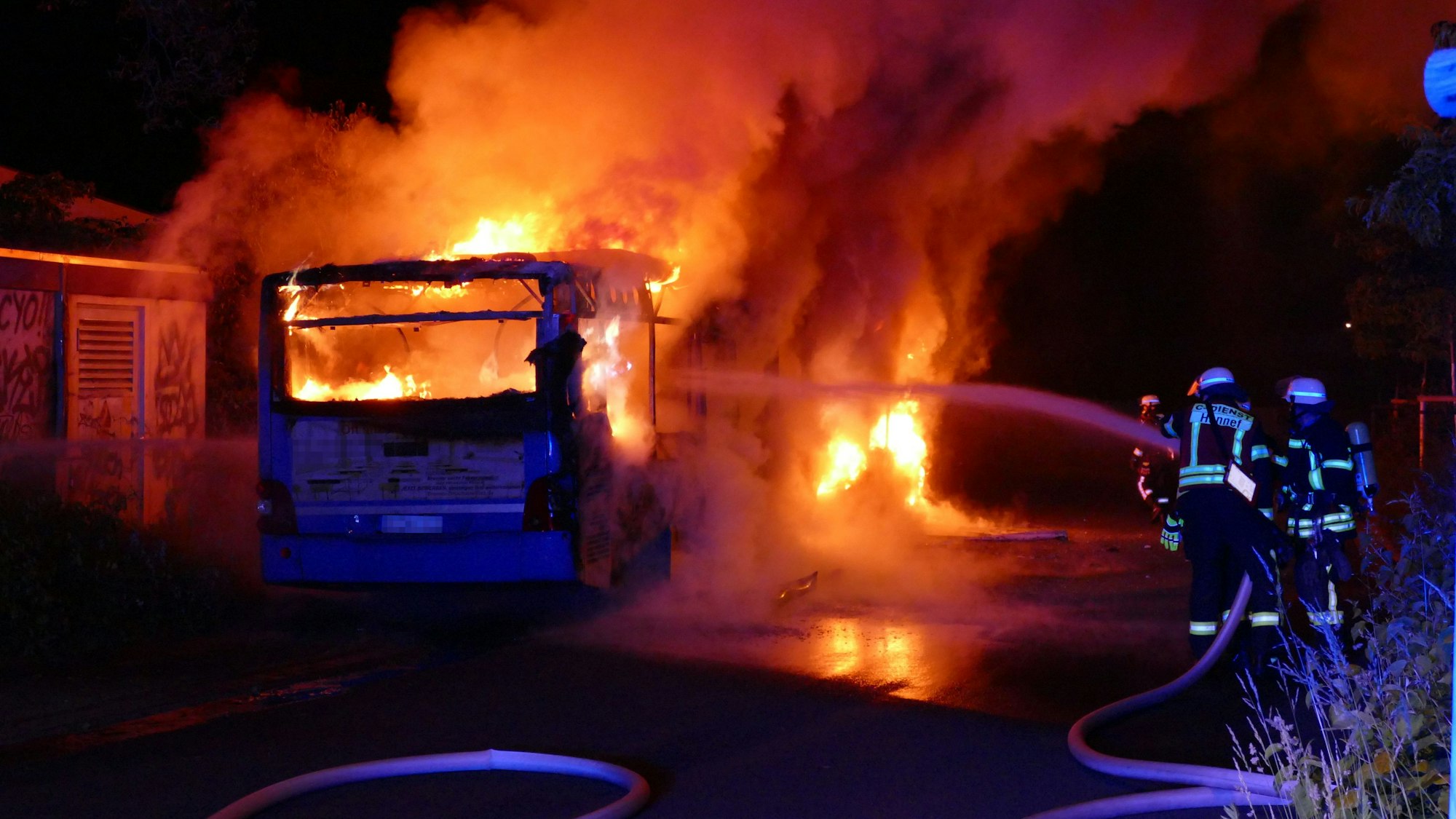 Feuerwehrleute löschen einen brennenden Bus.