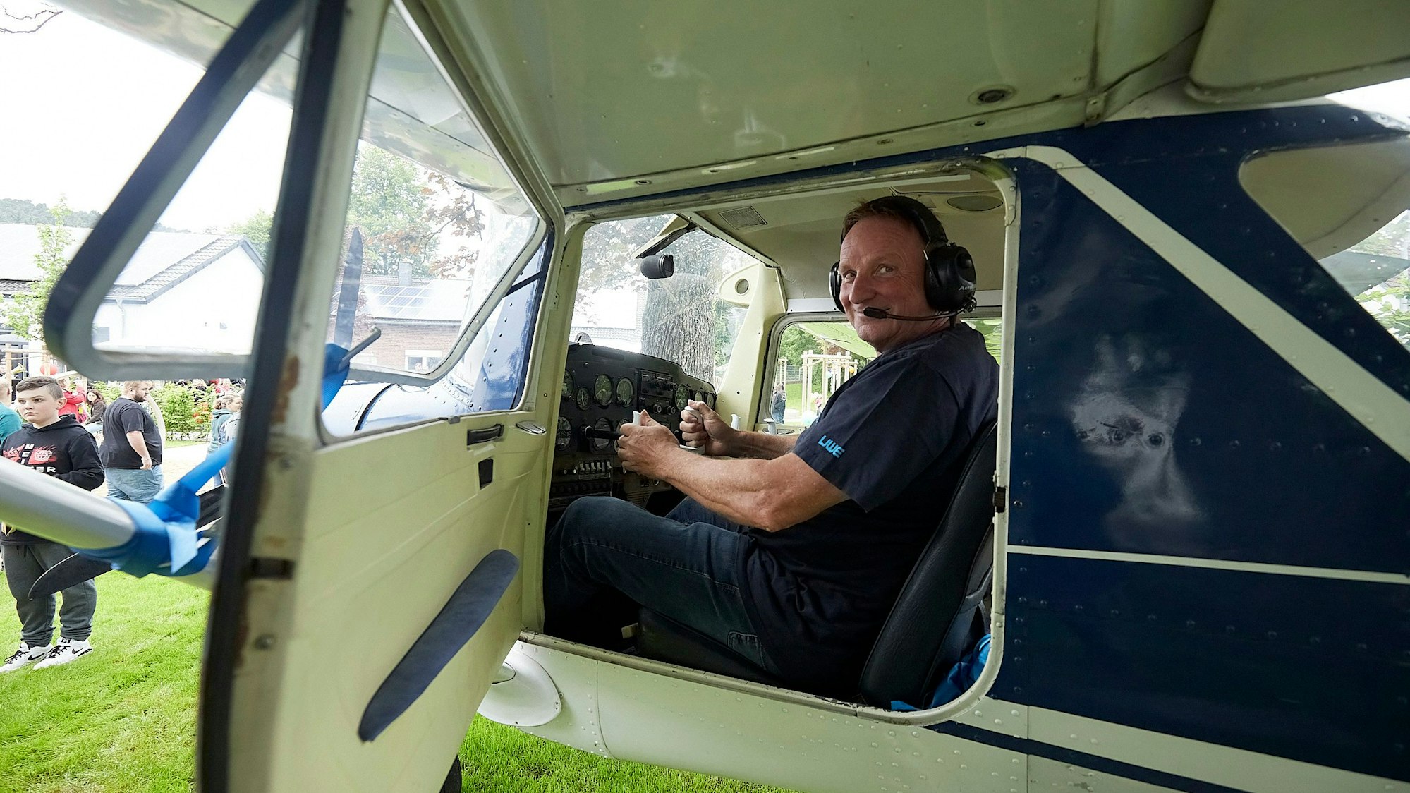 Ein Mann sitzt am Steuer einer blau-weißen Cessna.