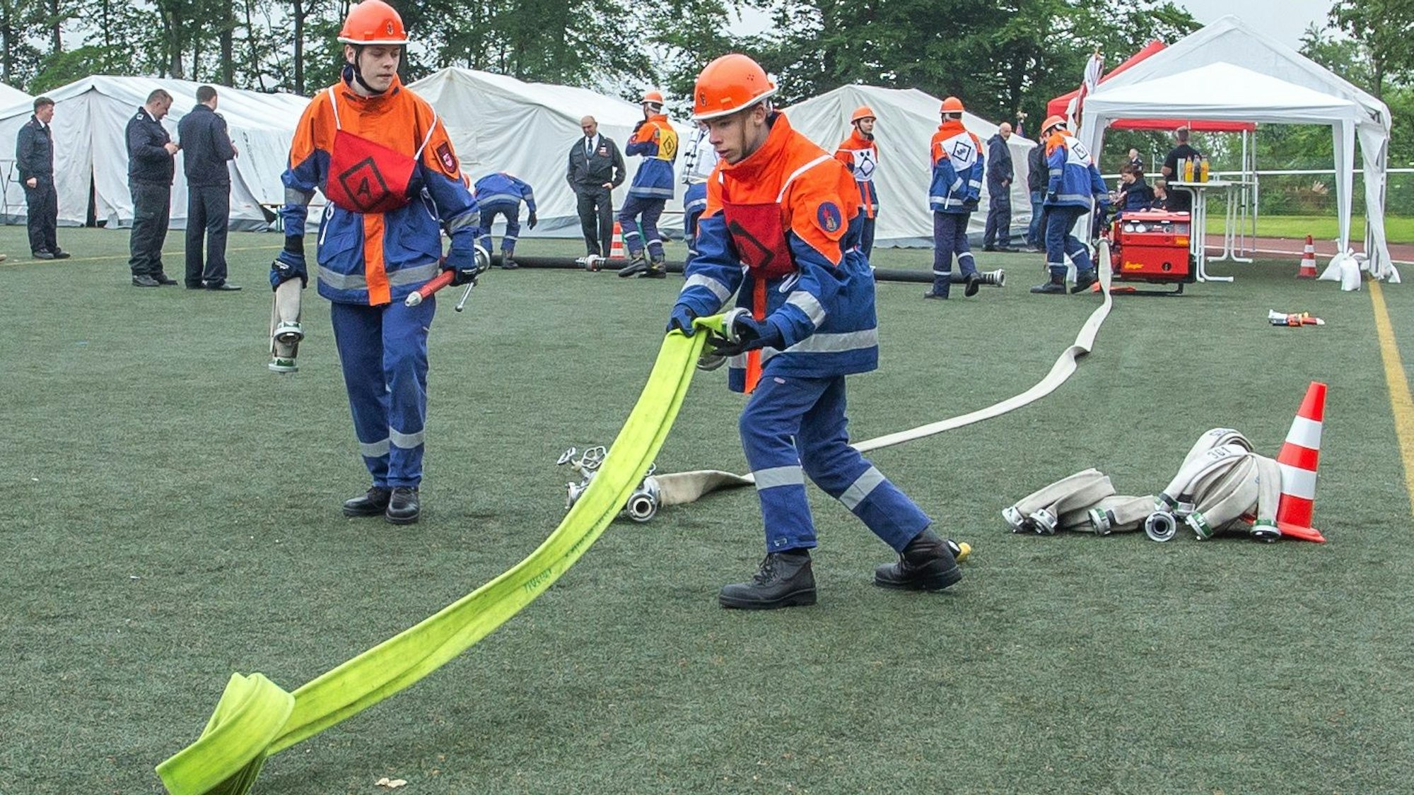 Zwei Jungs von der Jugendfeuerwehr rollen einen Schlauch aus.