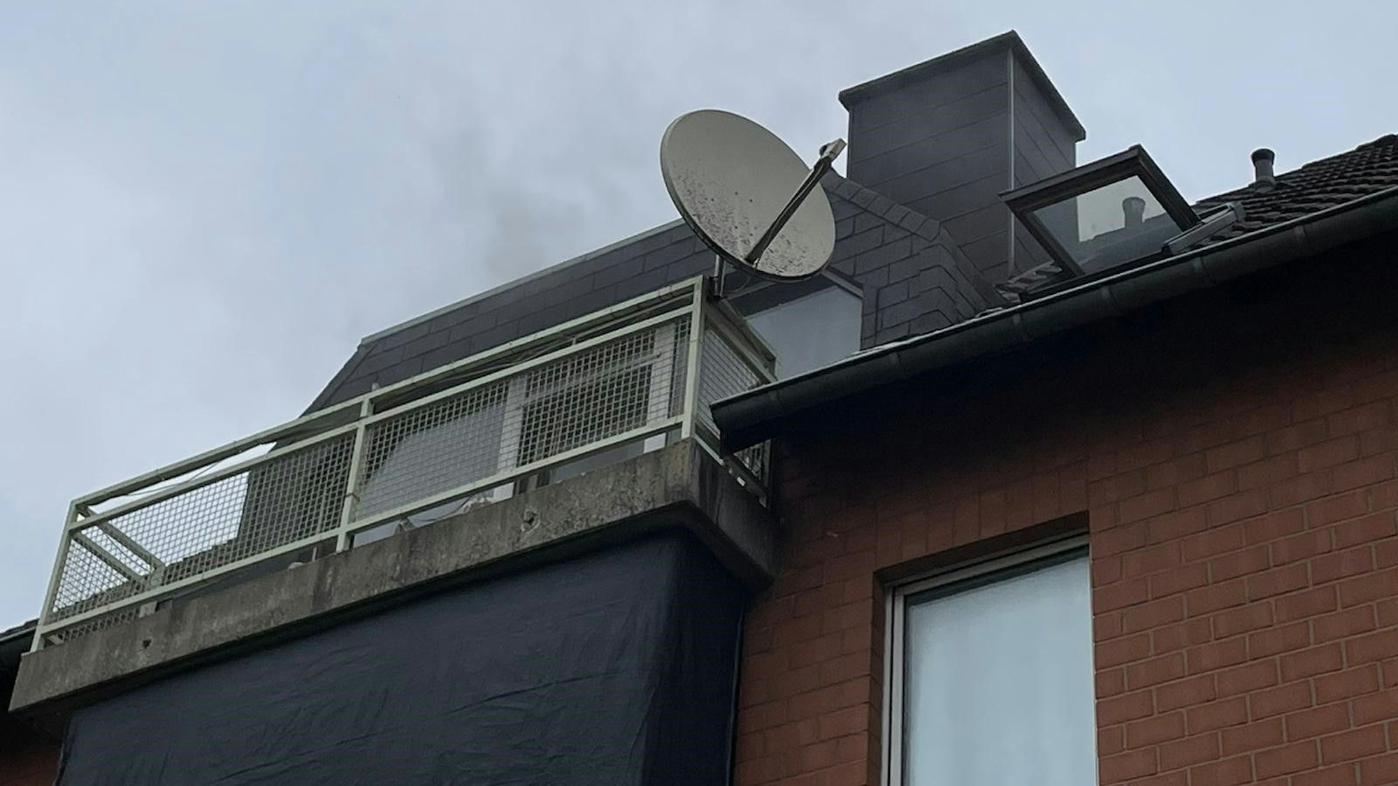 Rauch steigt aus dem Dach eines Mehrfamilienhauses in Bergheim auf.