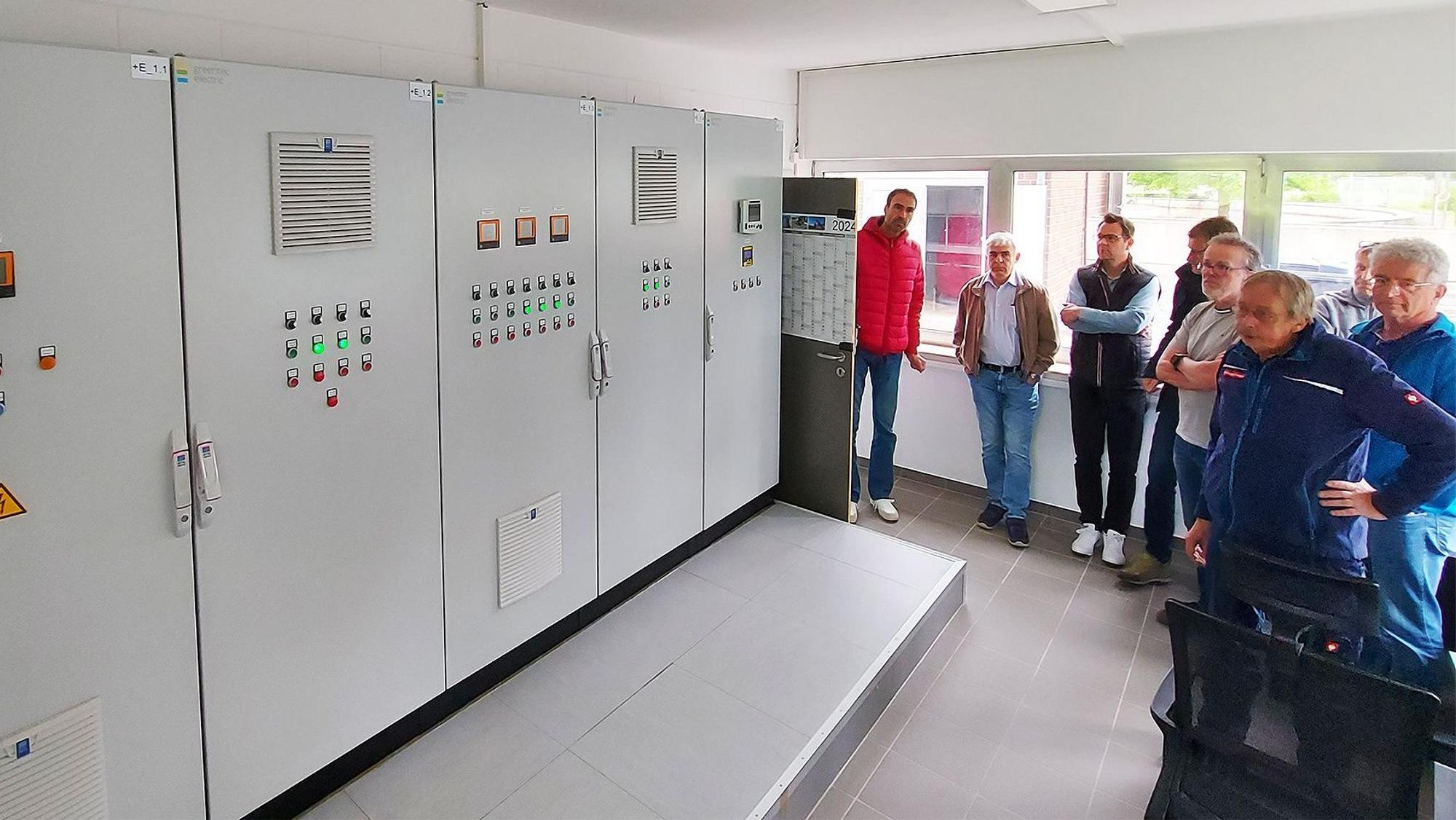 Mehrere Männer begutachten die Schaltanlage im Betriebsgebäude der Kläranlage Kronenburg.