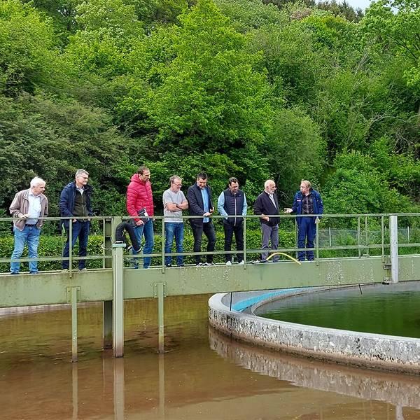 Mehrere Männer stehen auf der Schieberbrücke über dem Belebungsbecken der Kläranlage in Kronenburg.