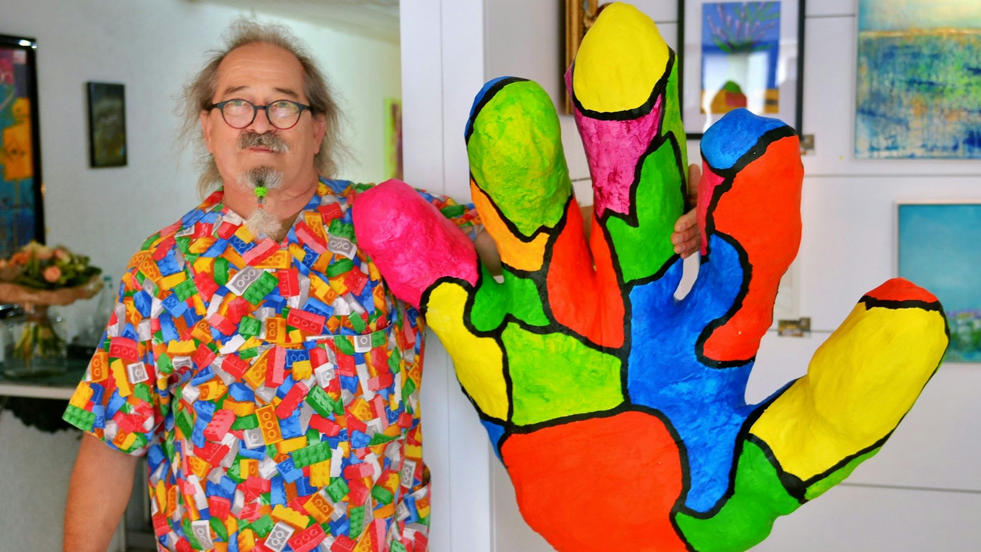 Künstler Uwe Rhiem zeigt seine bunte Handskulptur. Sie ist mehr als einen Meter hoch.