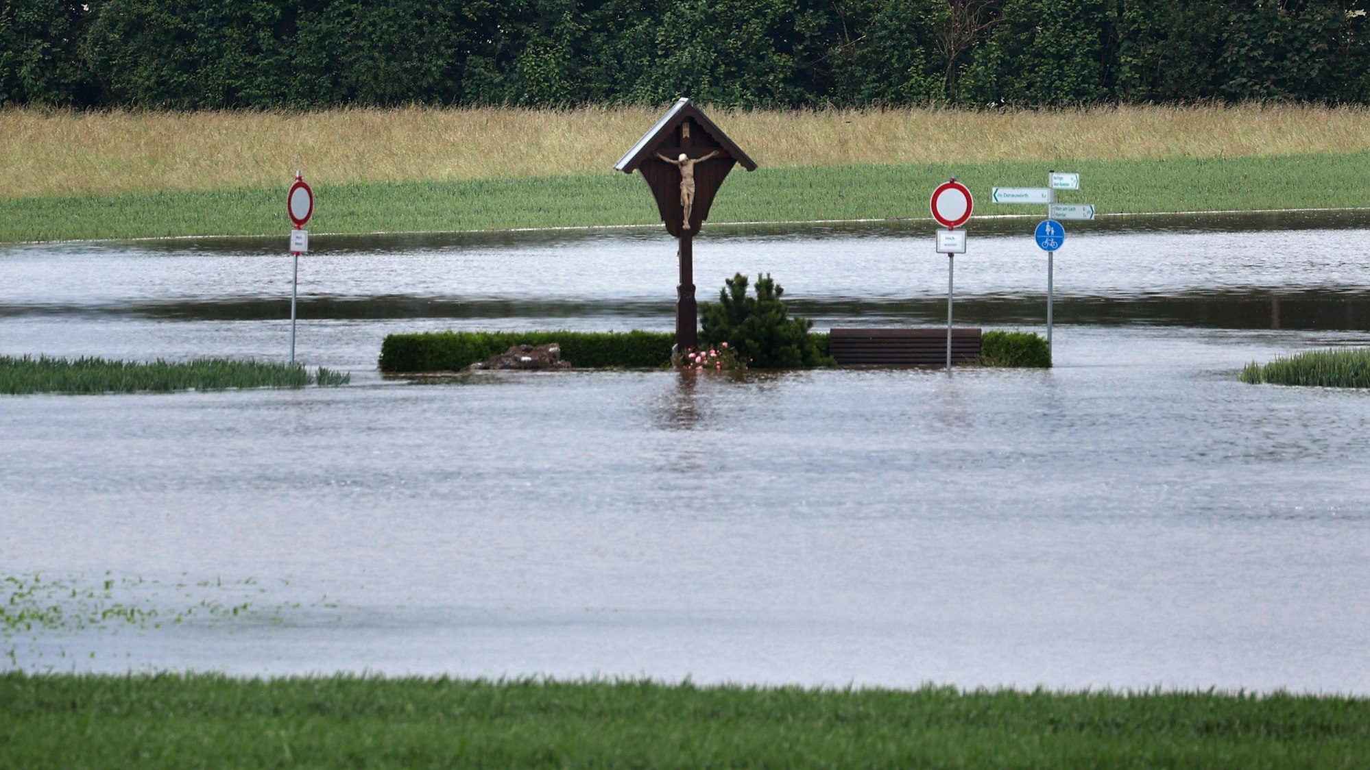 Ein Wegkreuz steht am Montag in der vom Hochwasser überfluteten Landschaft nahe Asbach-Bäumenheim in Bayern.