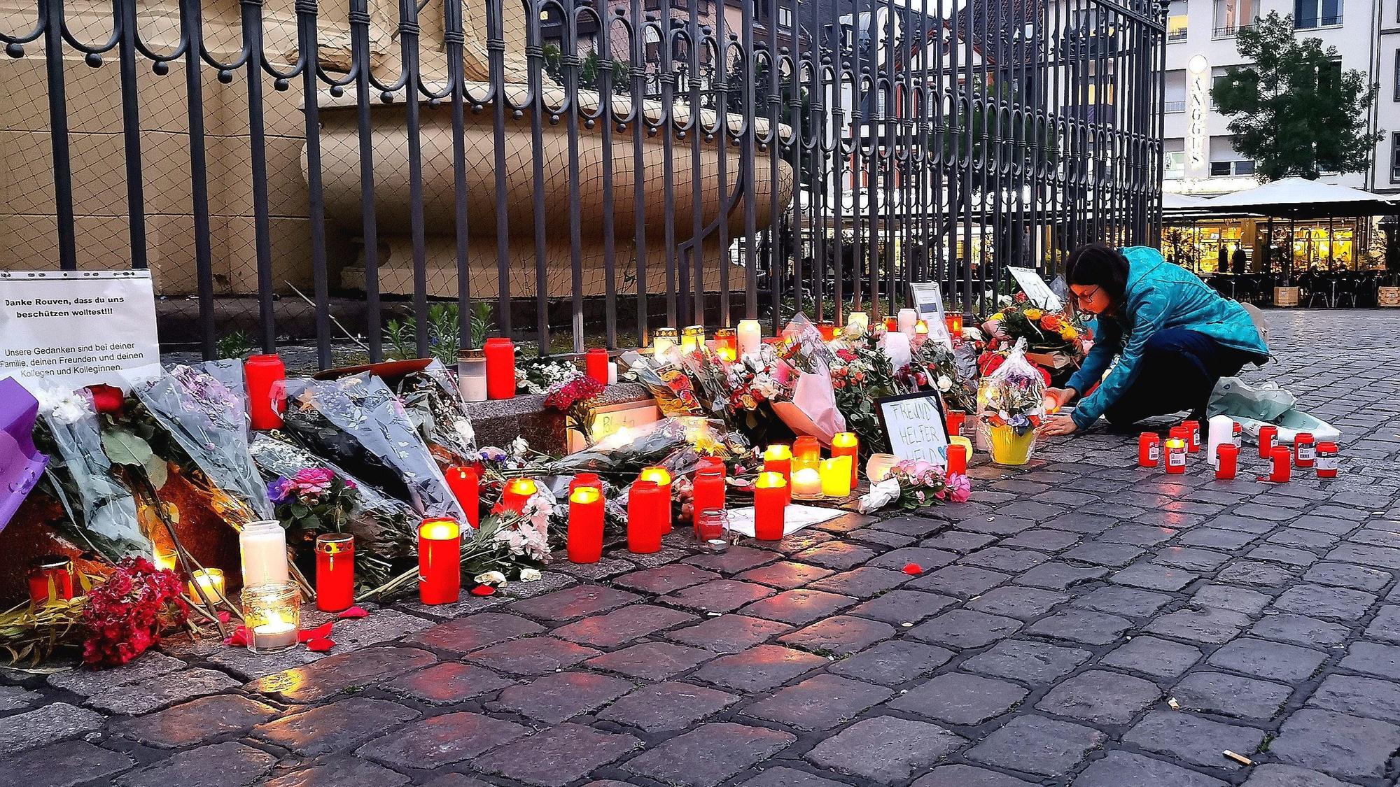 Nach dem Bekanntwerden vom Tod des Polizisten legen am Tatort am Marktplatz Passanten Blumen nieder und zünden Kerzen an. Der Polizist war hier von einem Mann mit einem Messer niedergestochen und lebensgefährlich verletzt worden.