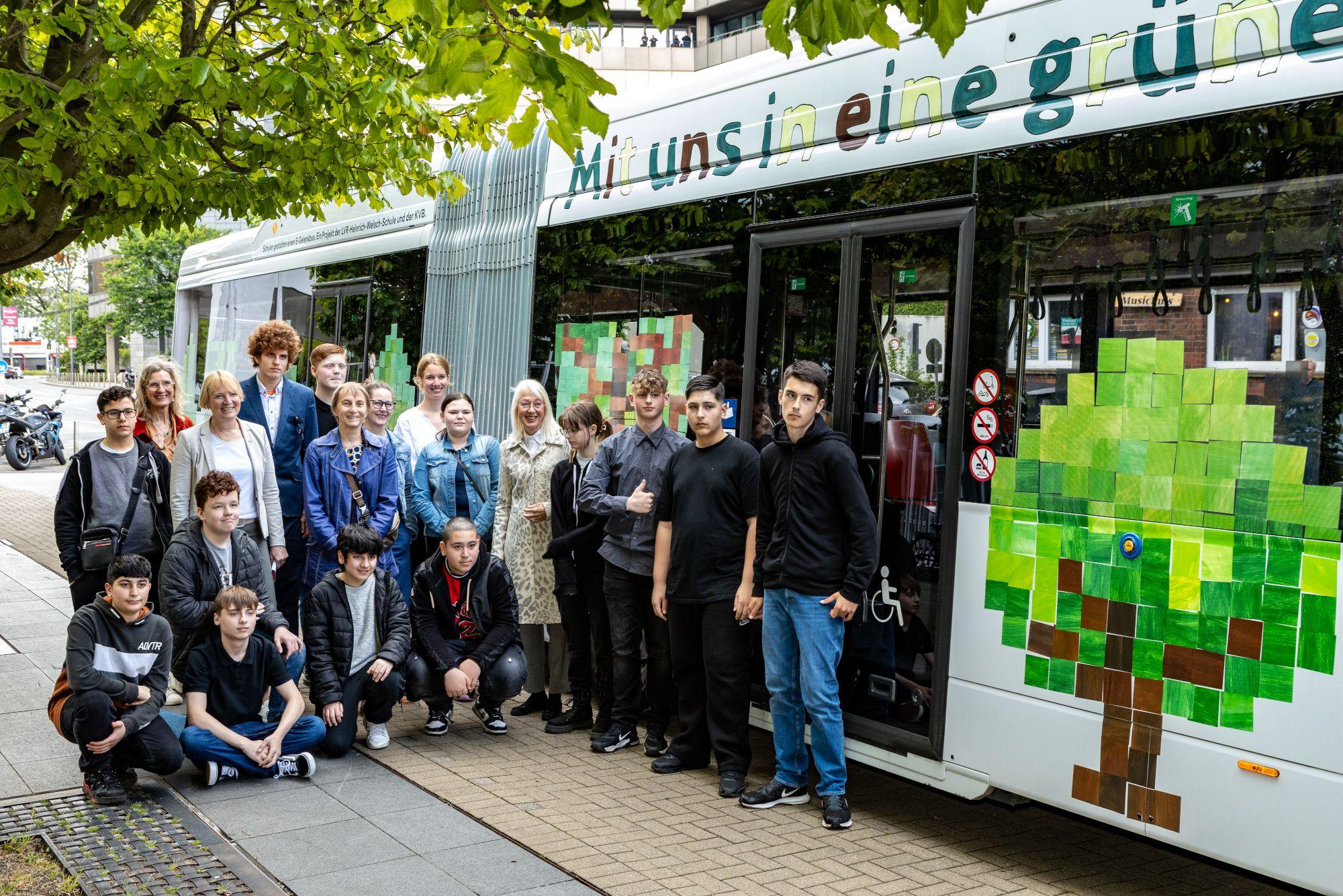 Die Schülerinnen und Schüler der LVR-Heinrich-Welsch-Schule mit der KVB-Vorstandsvorsitzenden Stefanie Haaks (hinten, 3.v.l.) und Schirmfrau Elfi Scho-Antwerpes (5.v.r.) vor dem gestalteten Bus.