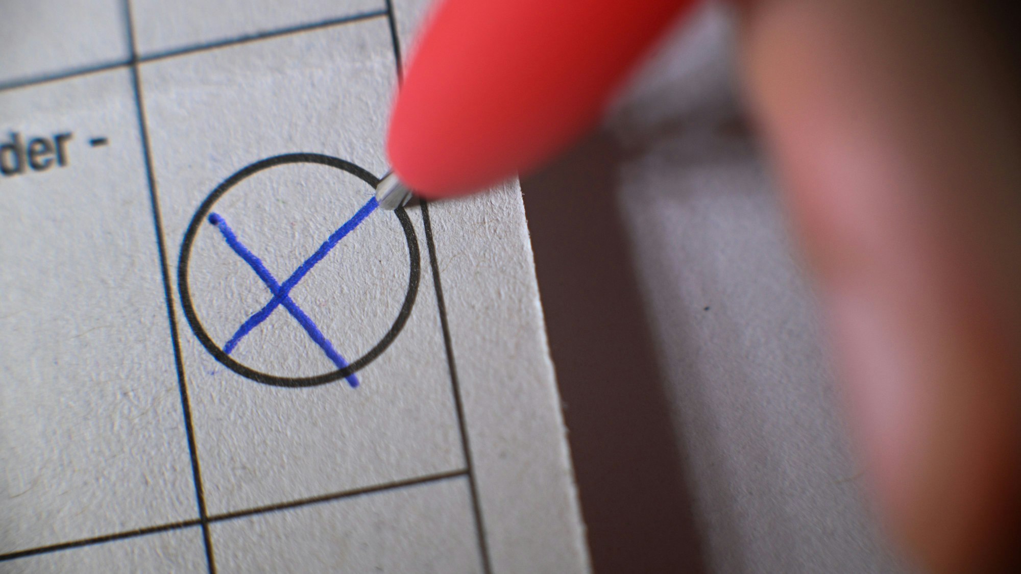 Eine Person kreuzt ein Kästchen auf einem Wahlzettel an.