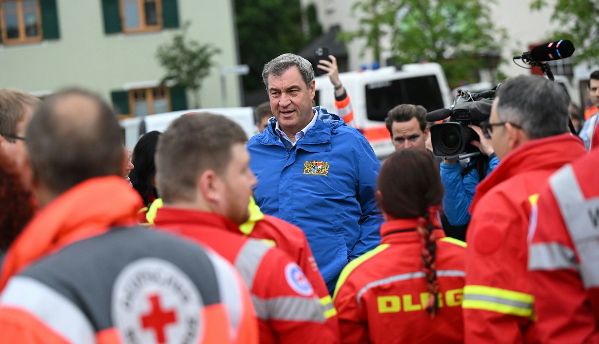 Bayerns Ministerpräsident Markus Söder (M, CSU) spricht zu Einsatzkräften verschiedener Rettungsdienste bei einer Ortsbesichtigung im vom Hochwasser betroffenen oberbayerischen Reichertshofen.