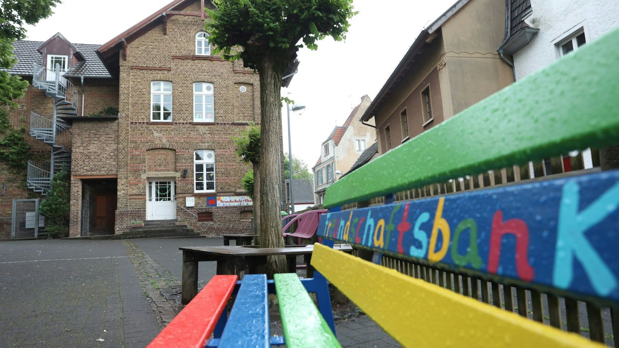 Eine bunte Sitzbank steht auf dem Schulhof.