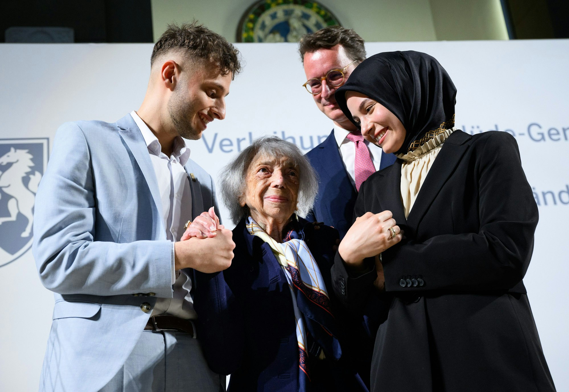 Rührende Szenen: Can Genc und Özlem Genc-Evran, zwei Enkel von Mevlüde Genc, nehmen Margot Friedländer in ihre Mitte. Ministerpräsident Hendrik Wüst hatte der Holocaust-Überlebenden zuvor die „Mevlüde-Genc-Medaille“ des Landes verliehen.