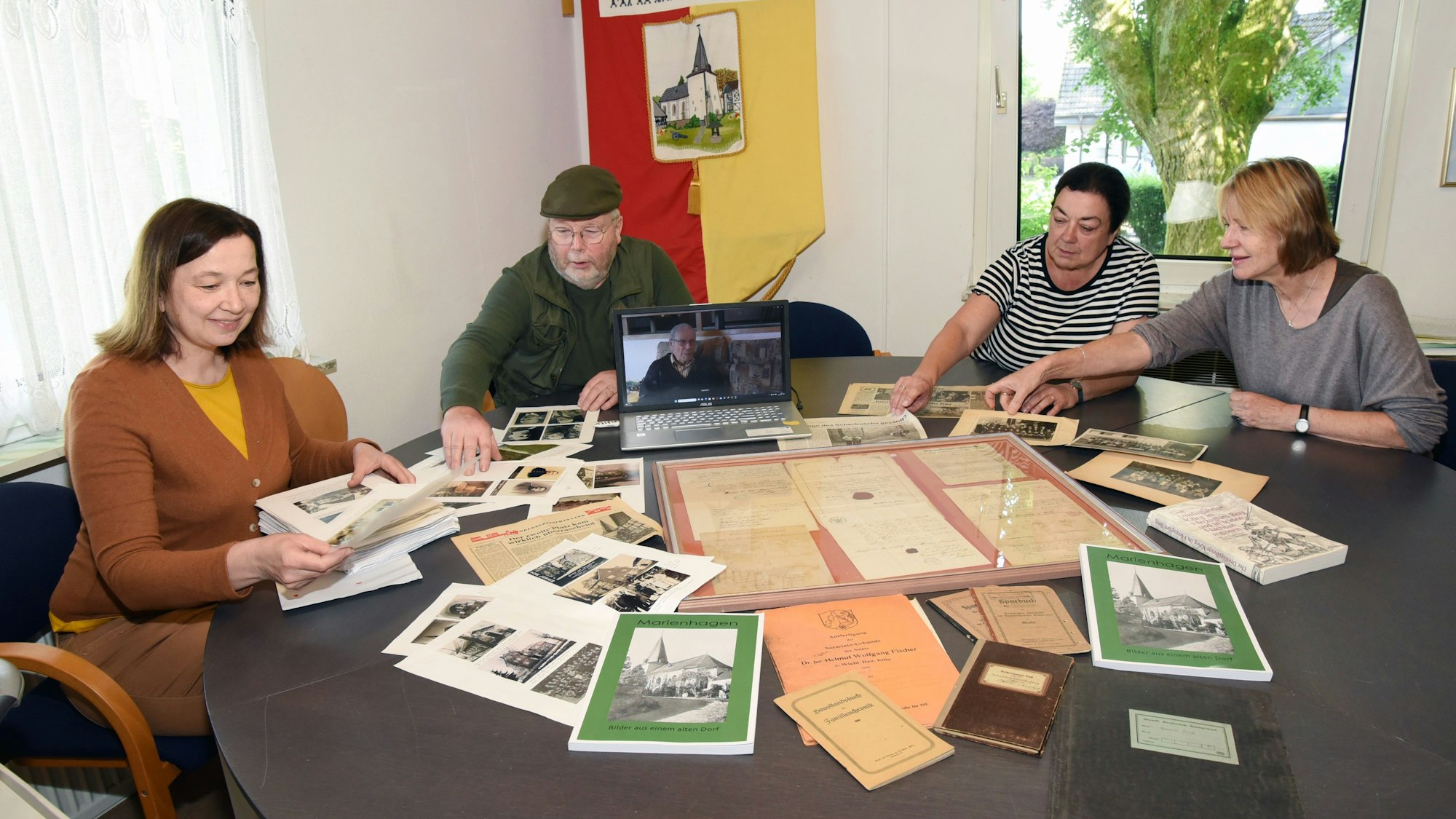In Marienhagen sitzen vier Menschen um einen Tisch, auf dem zahlreiche alte Dokumente liegen.