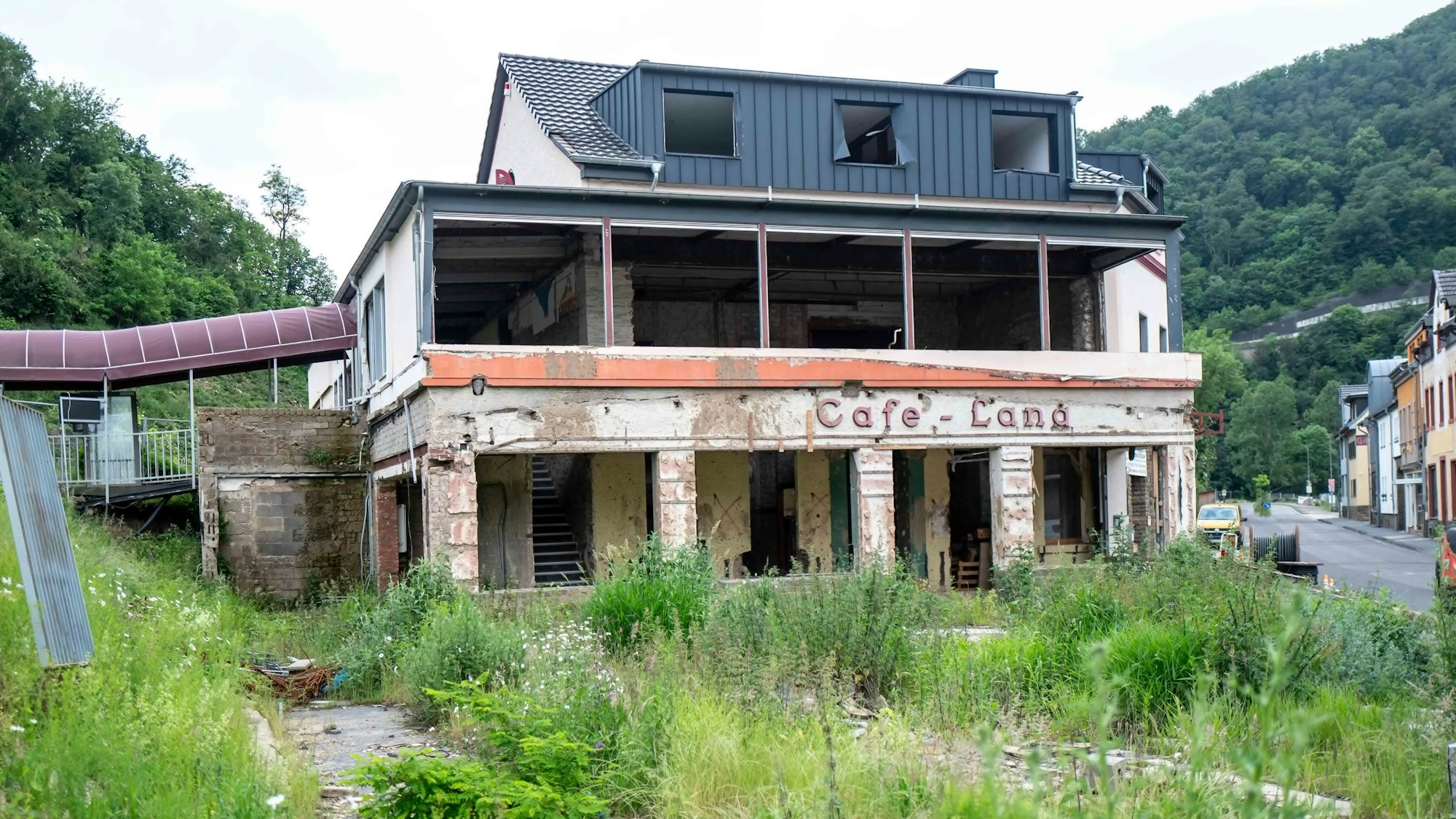 Das einstige Café Lang in Altenahr ist nach der Flutkatastrophe von 2021 noch nicht wieder aufgebaut. Das Haus steht leer, es sind keine Fenster vorhanden. Vor dem Haus wuchert Unkraut.