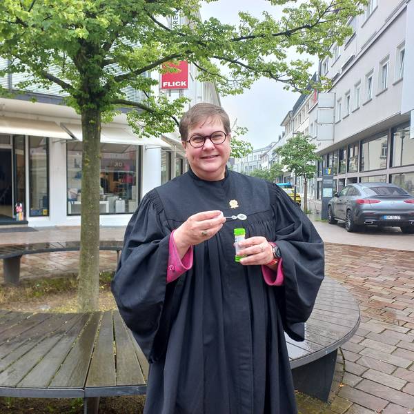 Pfarrerin Anneke Ihlenfeldt im Porträt. In den Händen hält sie eine kleine Röhre mit Seifenblasenflüssigkeit.