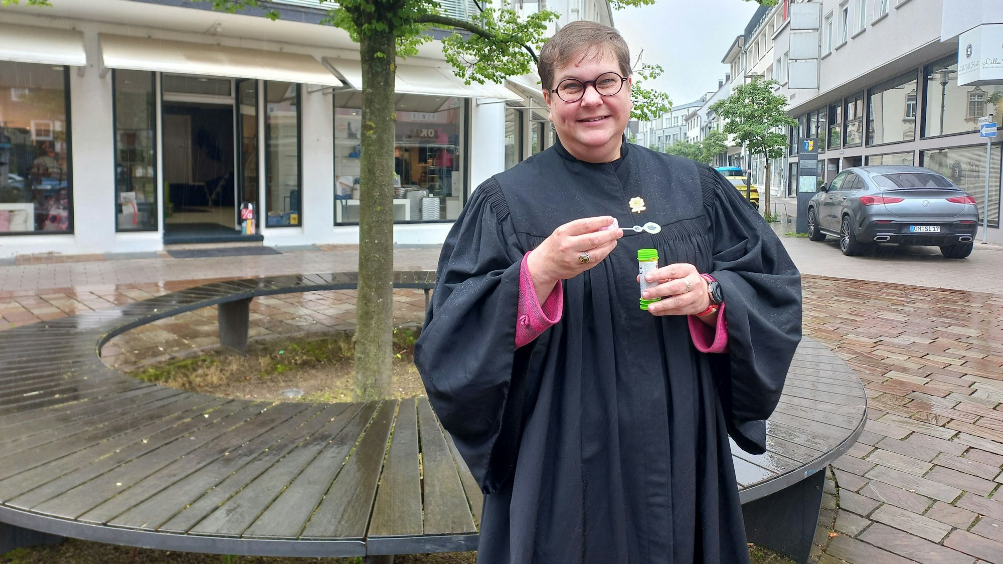 Pfarrerin Anneke Ihlenfeldt im Porträt. In den Händen hält sie eine kleine Röhre mit Seifenblasenflüssigkeit.