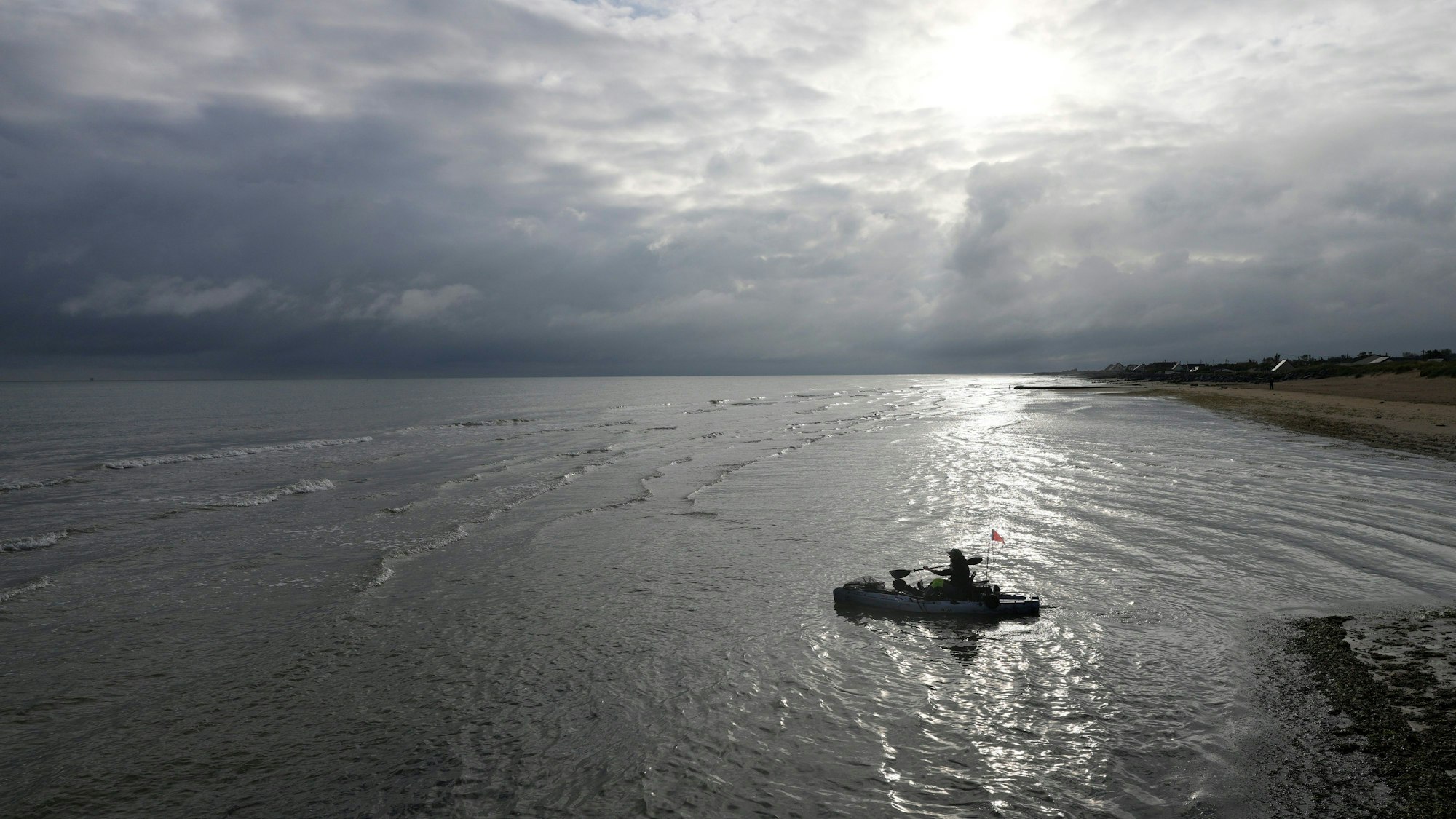 Ein Feuerwehrmann paddelt mit seinem Boot vom Gold Beach der D-Day-Invasion bei Asnelles in der Normandie hinaus.