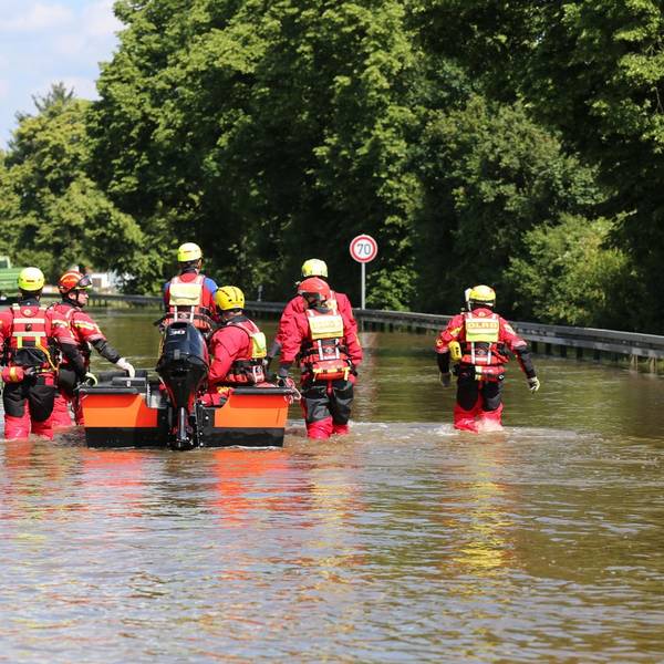 Das Foto zeigt Wasserretter des DLRG, die im Hochwasser waten.
