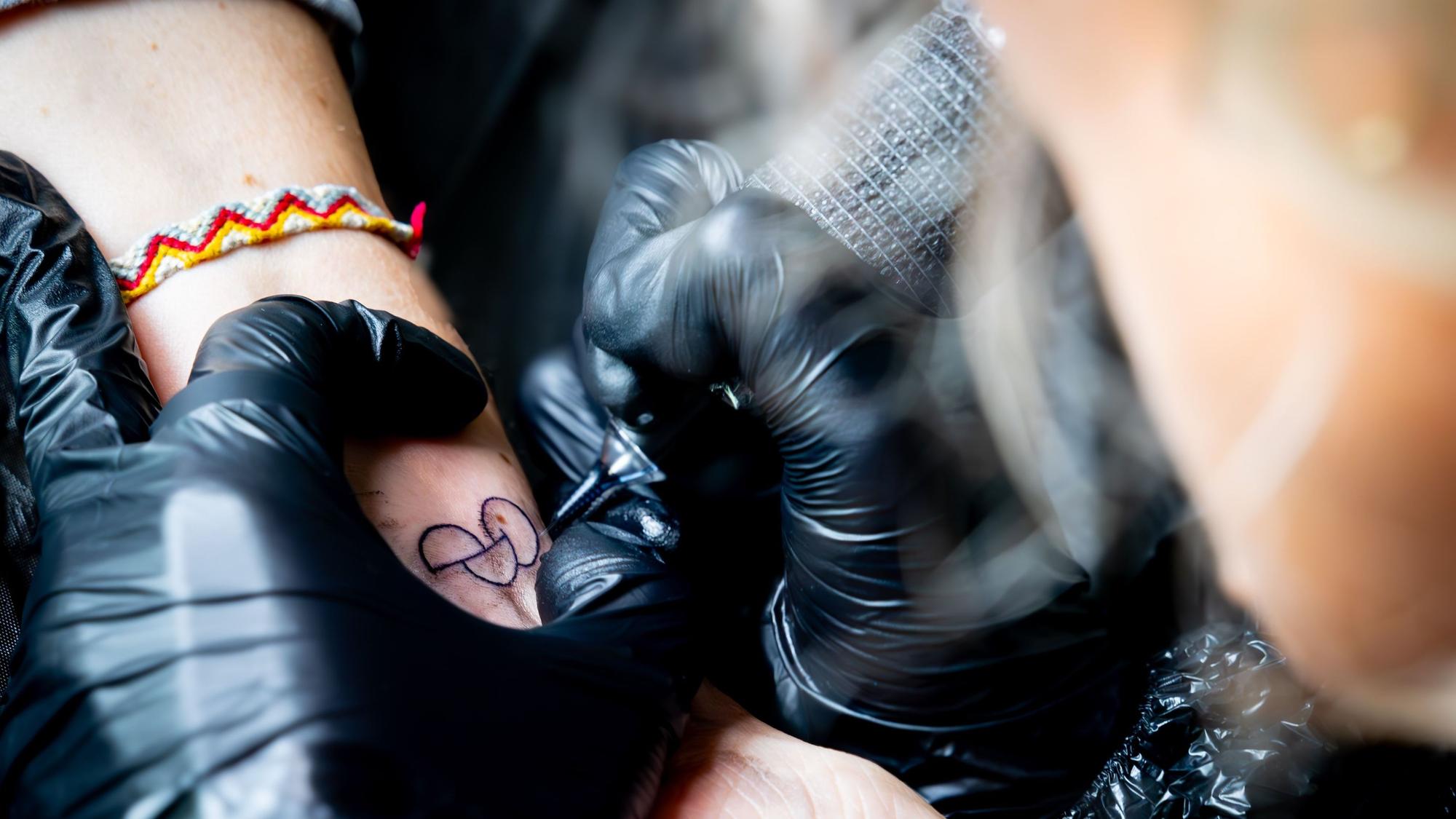 Eine Tätowiererin sticht das Tattoo.