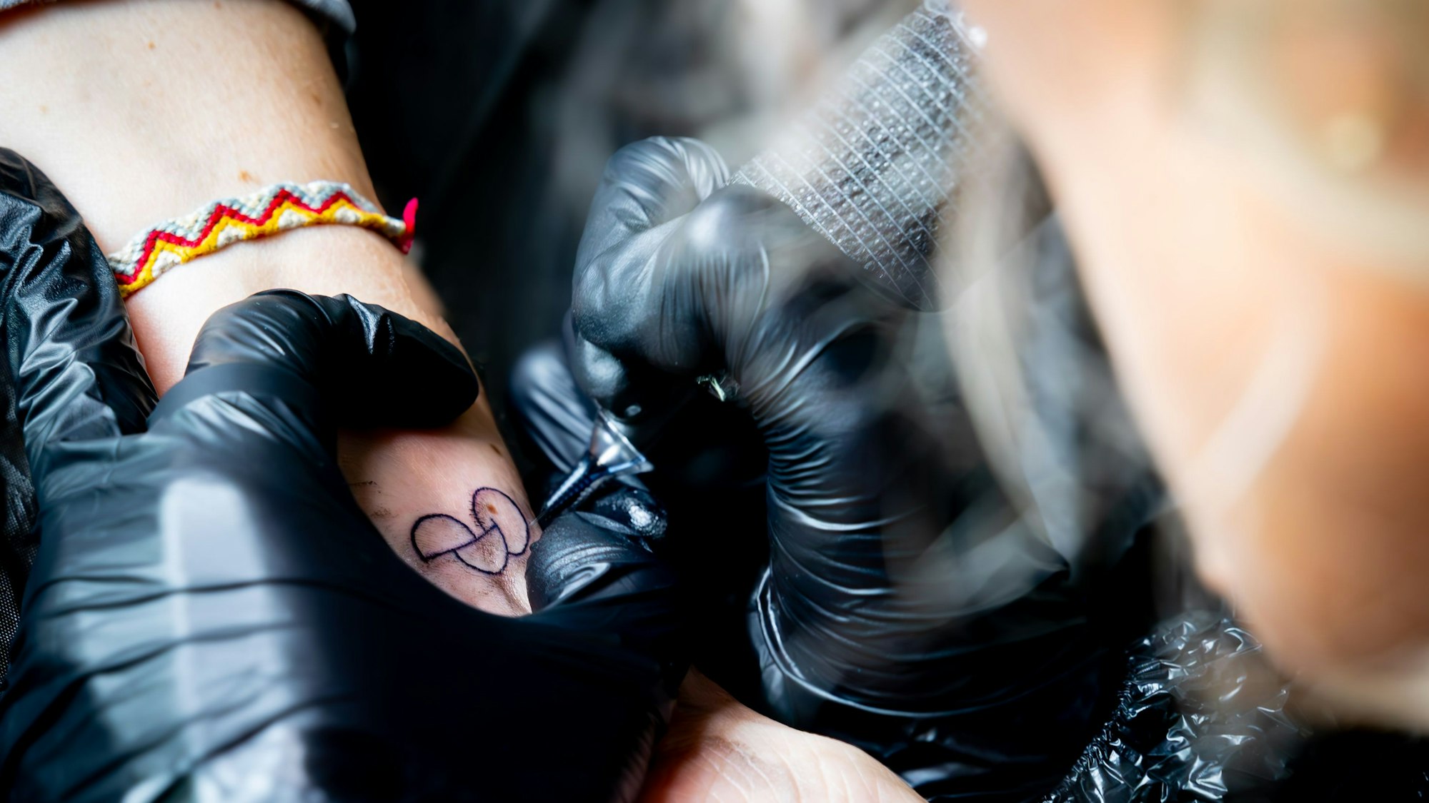 Eine Tätowiererin sticht das Tattoo.