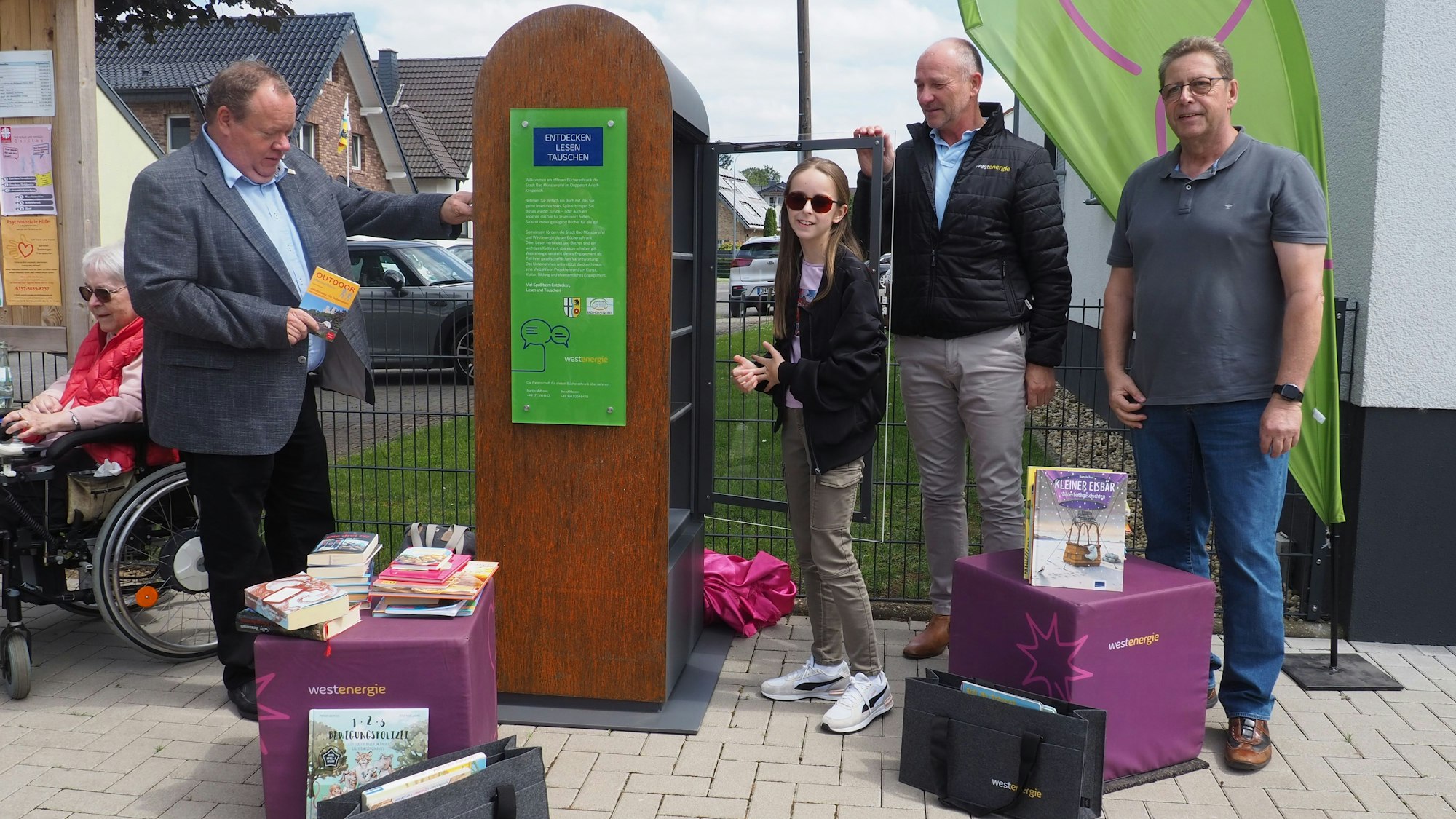 Kurt Reidenbach und Lilian Preise stellen Bücher in den öffentlichen Bücherschrank, Achim Diewald und Martin Mehrens schauen zu.