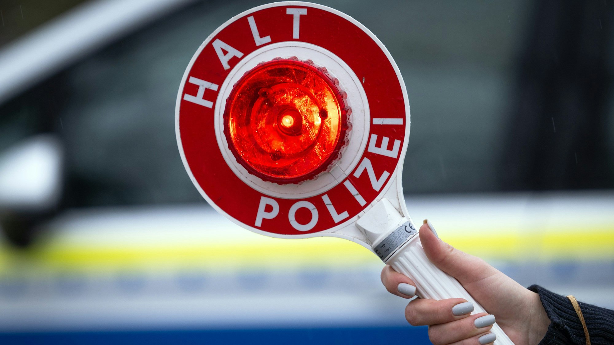 Eine Polizistin hält während einer Verkehrskontrolle an der Berliner Straße eine Polizeikelle.