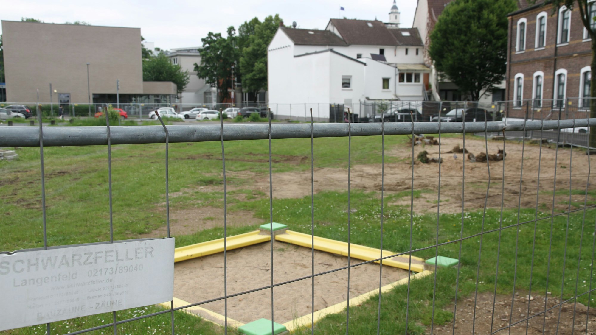 Ein Sandkasten hinter einem Bauzaun