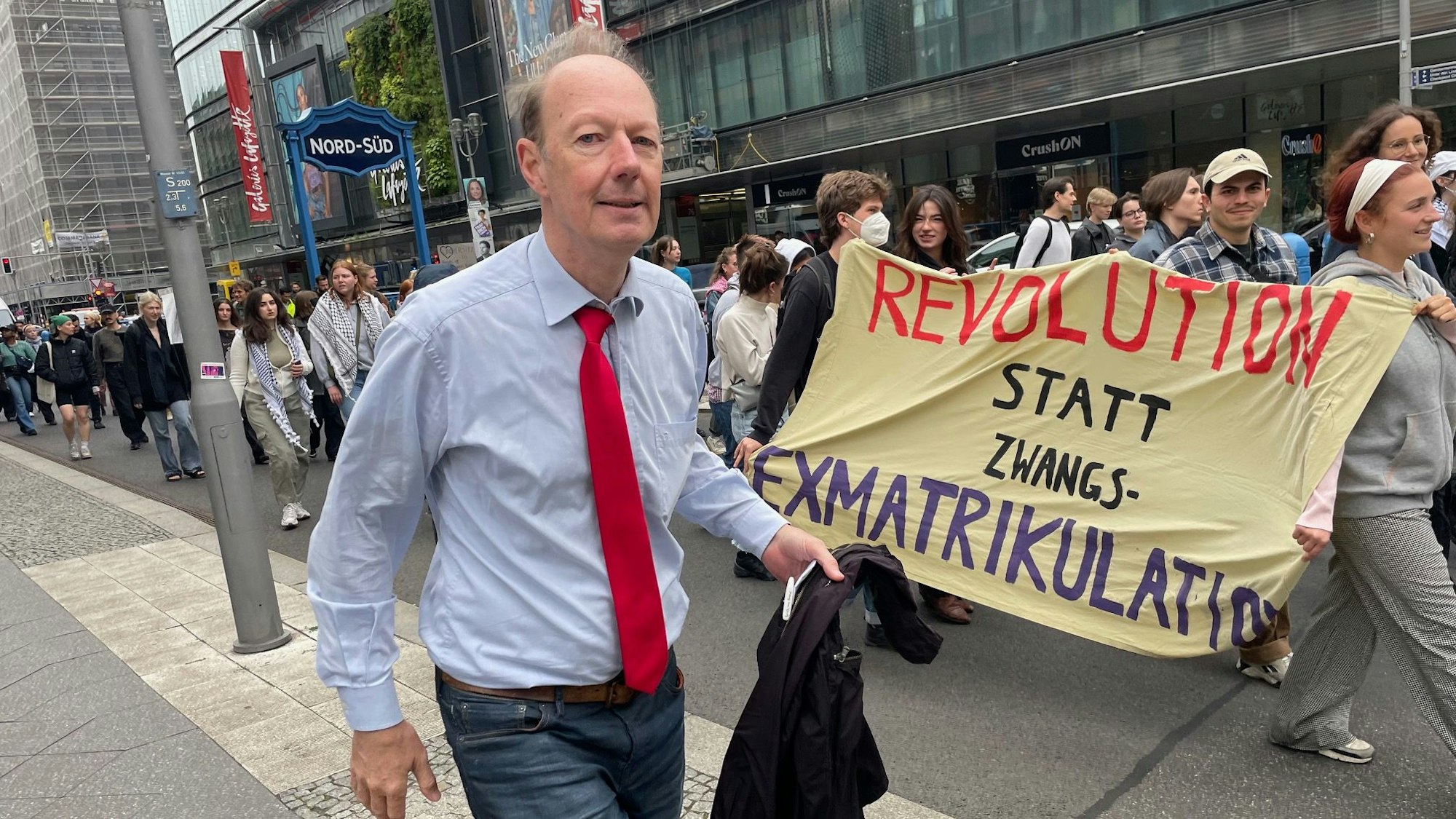 Martin Sonneborn geht in Berlin an Demonstranten vorbei.