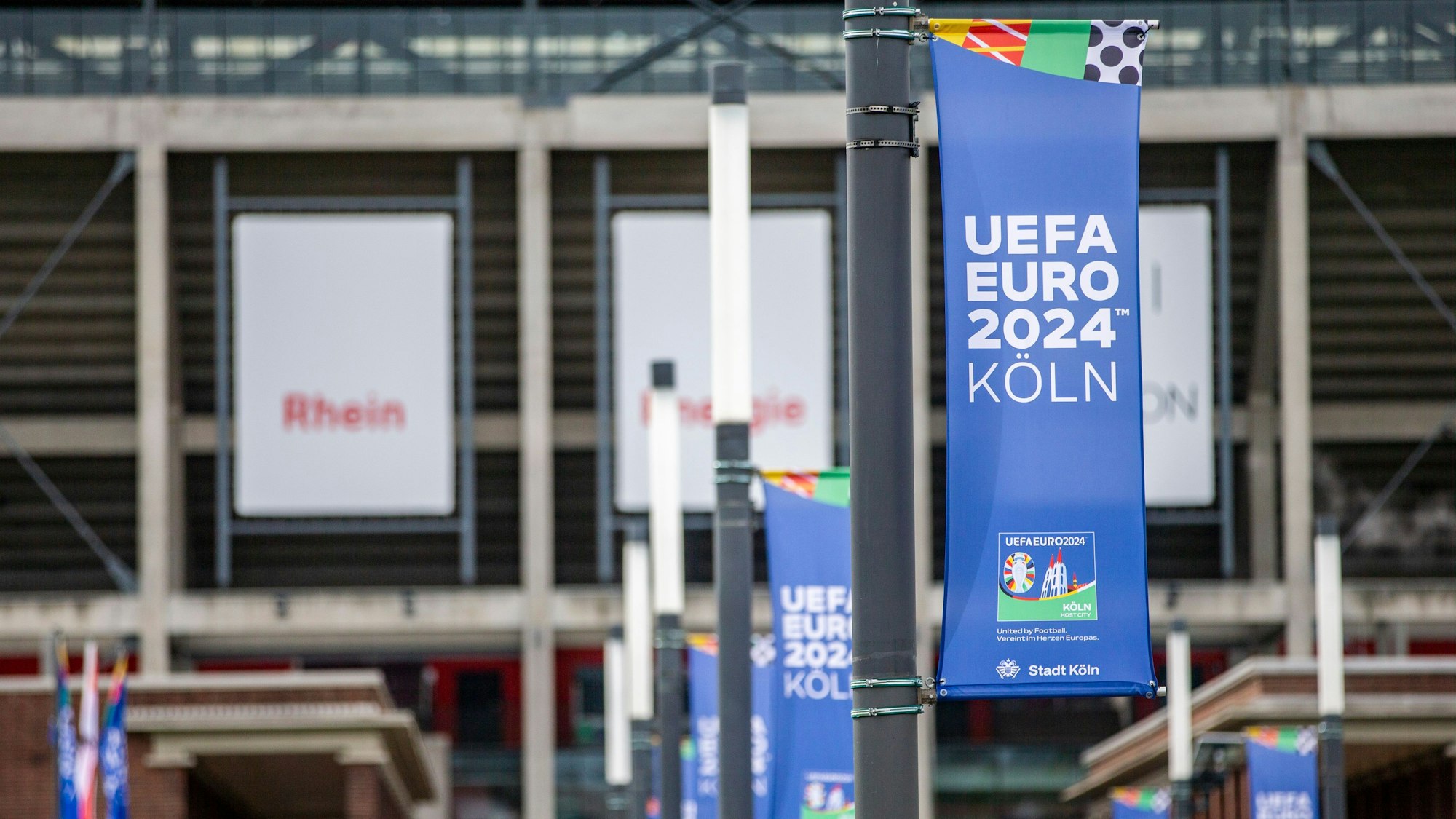 Am Rhein Energie Stadion hängen Fahnen, die auf die Fußball-EM hinweisen.