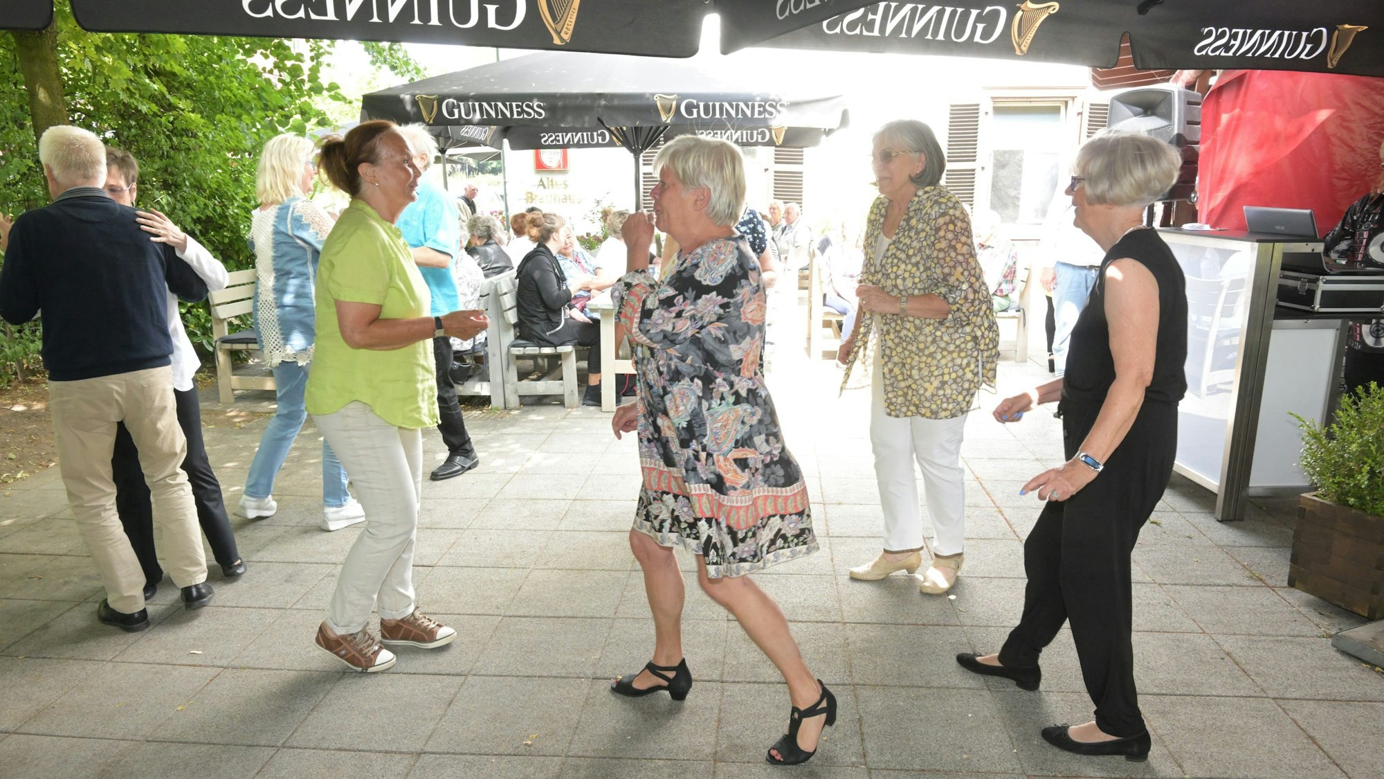 Tanzende Frauen und ein Pärchen unter einem Sonnenschirm.