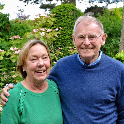 Karlheinz Schrade und seine Ehefrau Barbara Schrade stehen in ihrem Garten und halten sich im Arm.