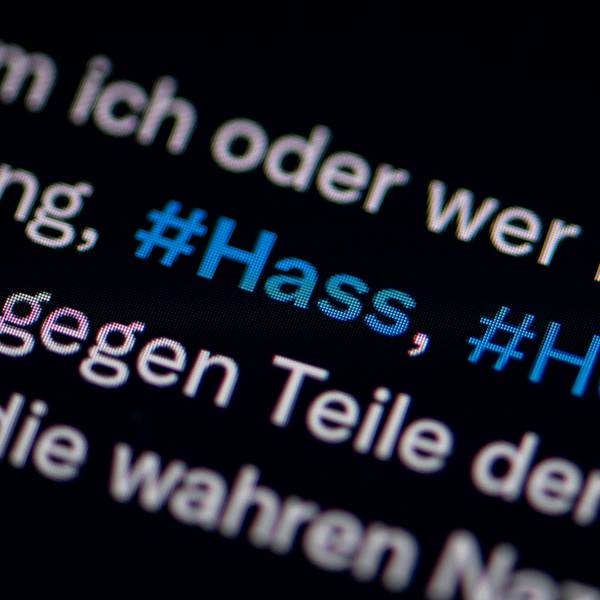 Auf dem Bildschirm eines Smartphones sieht man die Hashtags (#) Hass und Hetze in einem Twitter-Post.