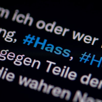 Auf dem Bildschirm eines Smartphones sieht man die Hashtags (#) Hass und Hetze in einem Twitter-Post.