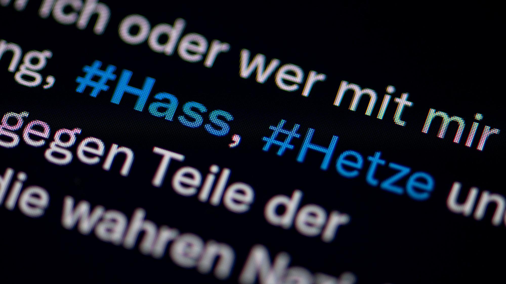 Auf dem Bildschirm eines Smartphones sieht man die Hashtags (#) Hass und Hetze in einem Twitter-Post.
