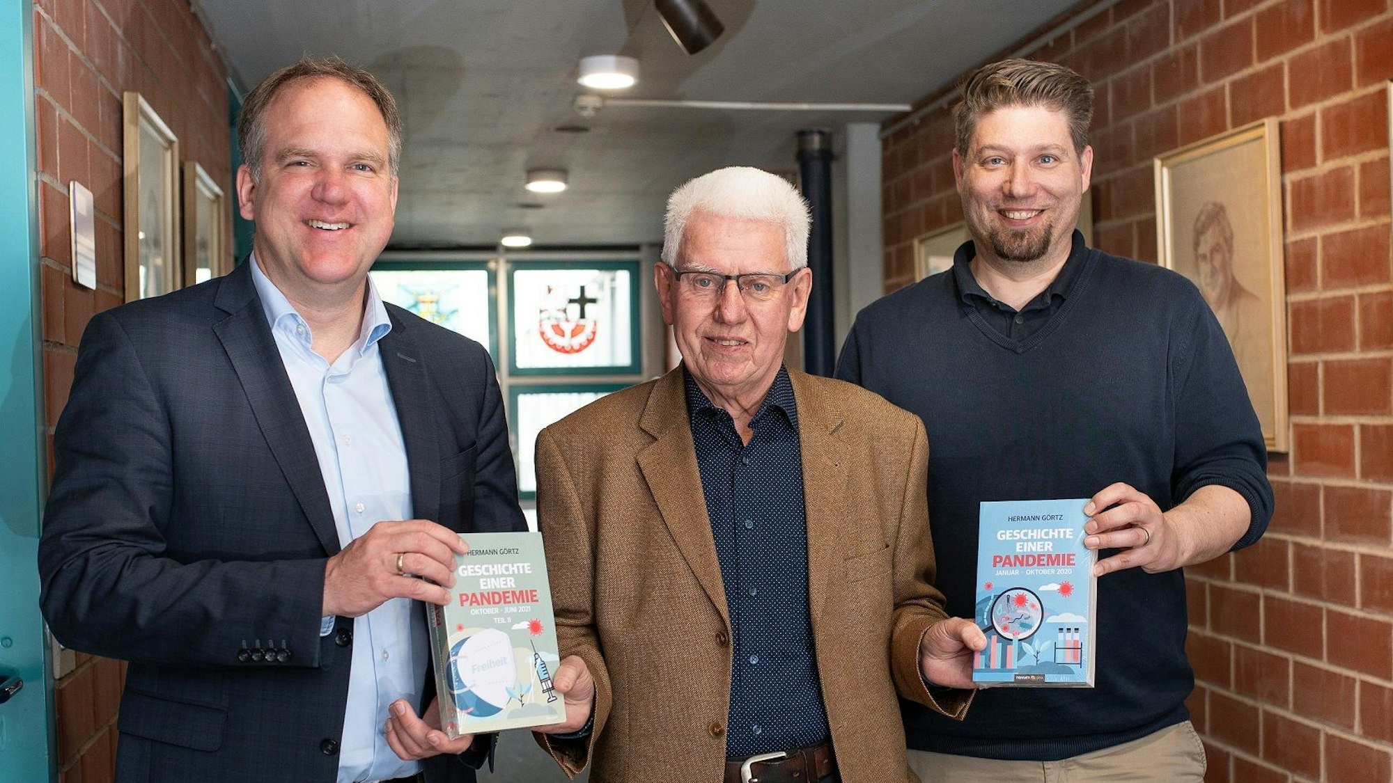 Bürgermeister Dirk Breuer und Stadtarchivar Michael Cöln nehmen aus den Händen von Autor Hermann Görtz die beiden Bücher entgegen.