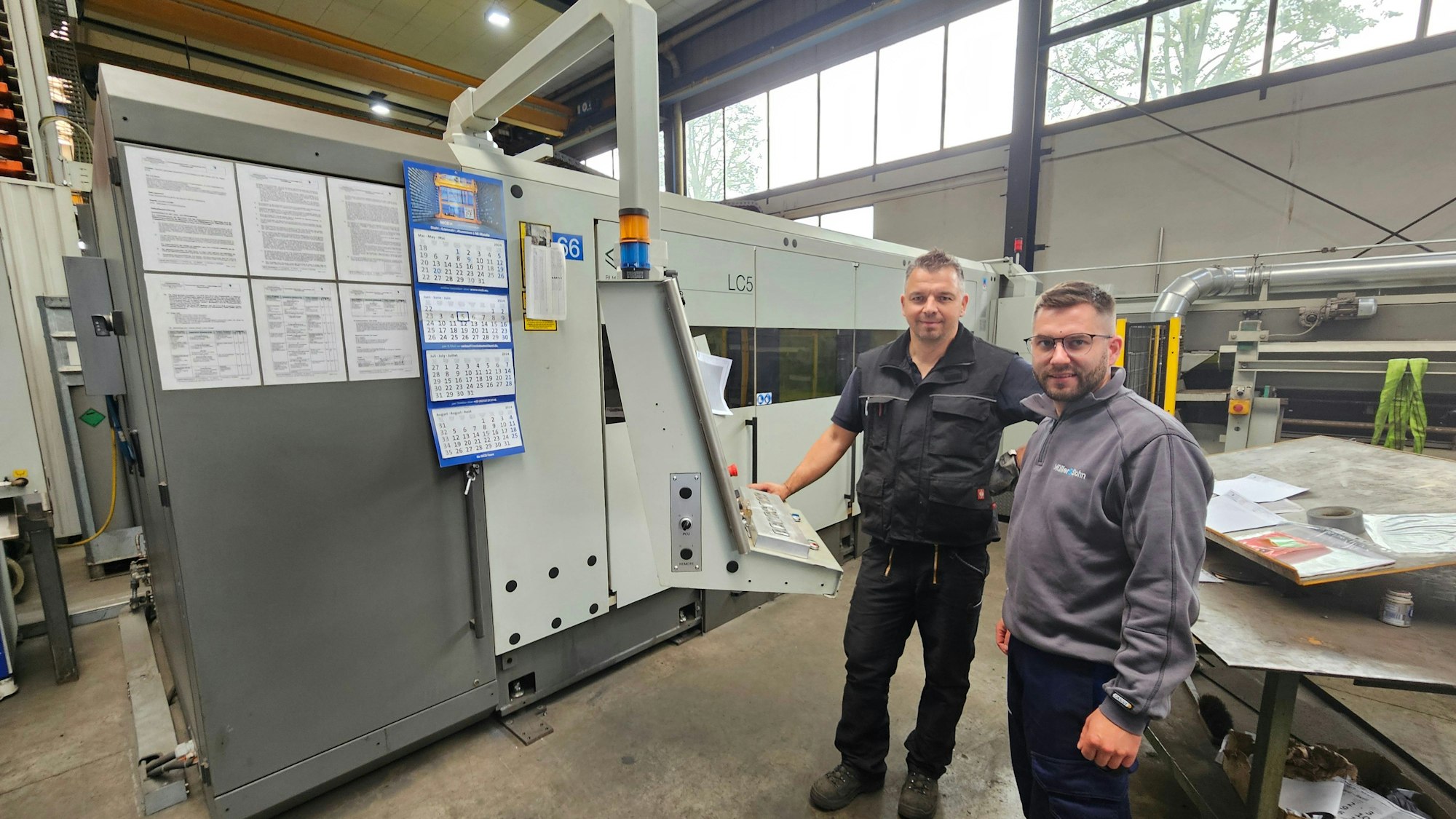 Rene Günther (l.) und Tobias Beume stehen neben dem Laserschneidegerät.