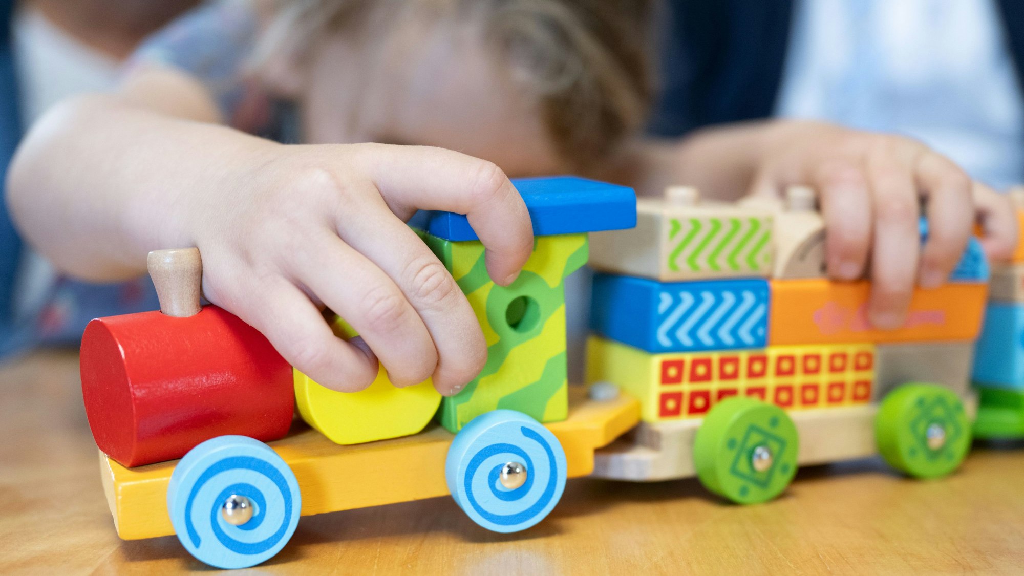 Das Foto zeigt ein Kind, das mit einer Spielzeug-Lokomotive spielt.